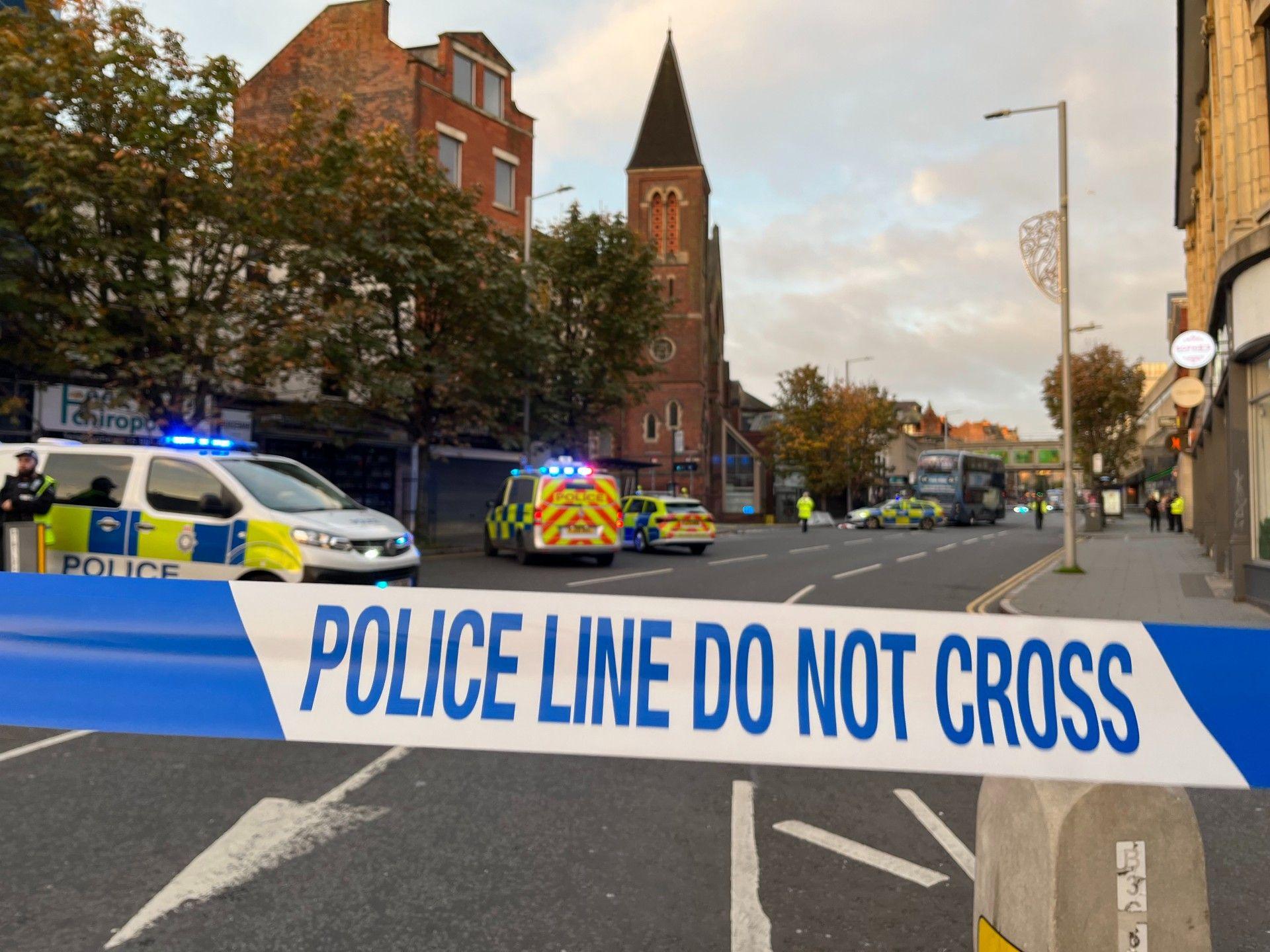 A police van, car and police officer parked outside of a Sainsbury's supermarket in Nottingham city centre