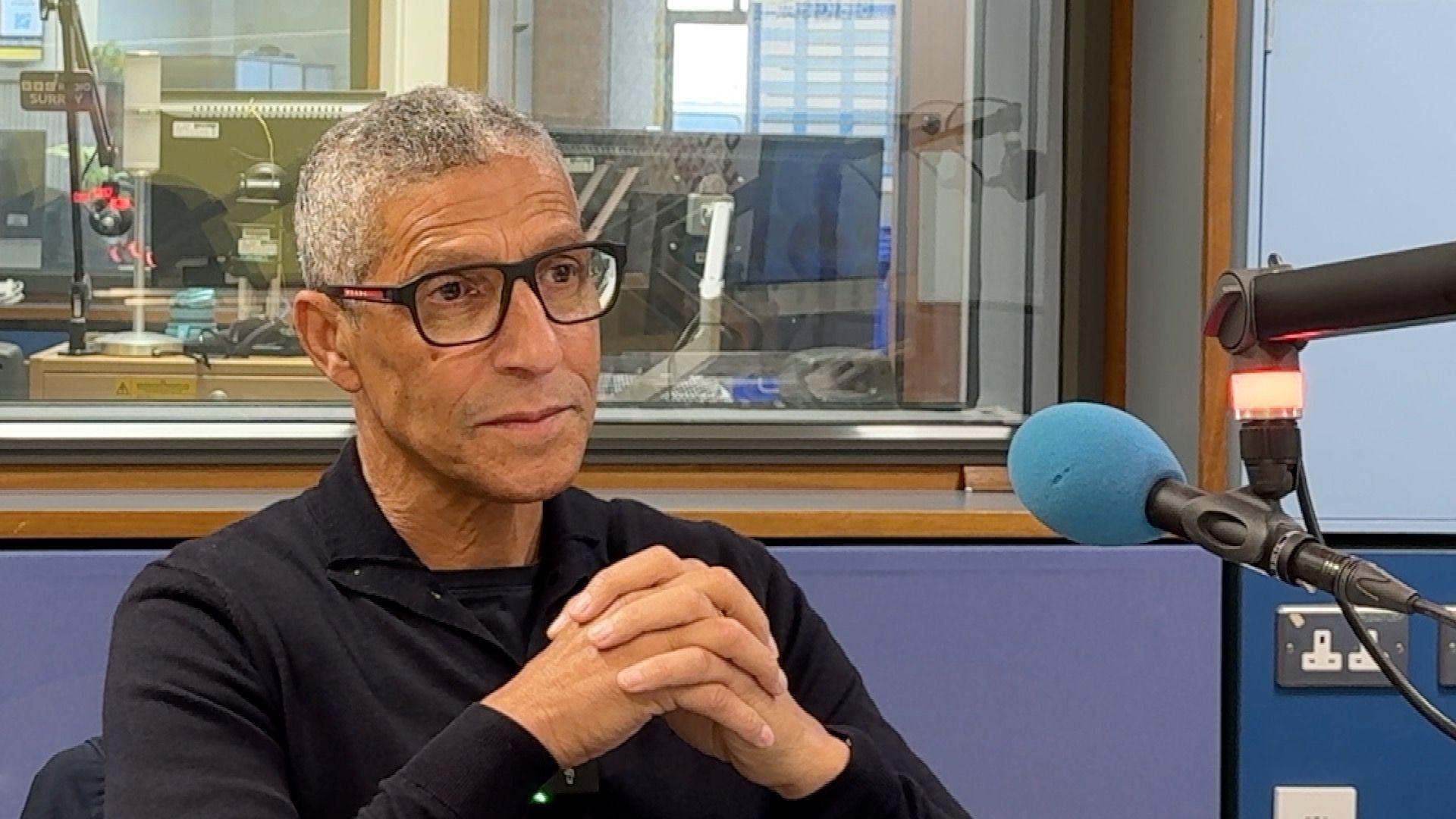 Chris Hughton wearing glasses, sat in BBC Radio Surrey's studio.