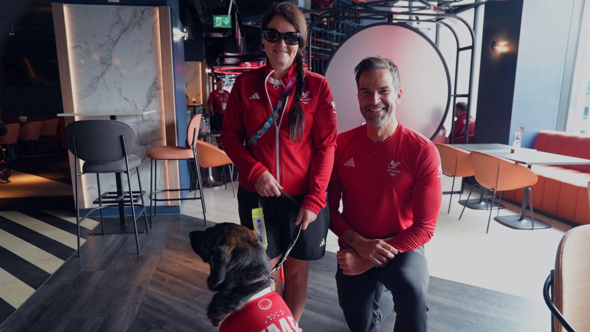Para-bowls player Julie Thomas and her guide dog Yoko pose for a photo with Team Wales chef de mission Gethin Jones.