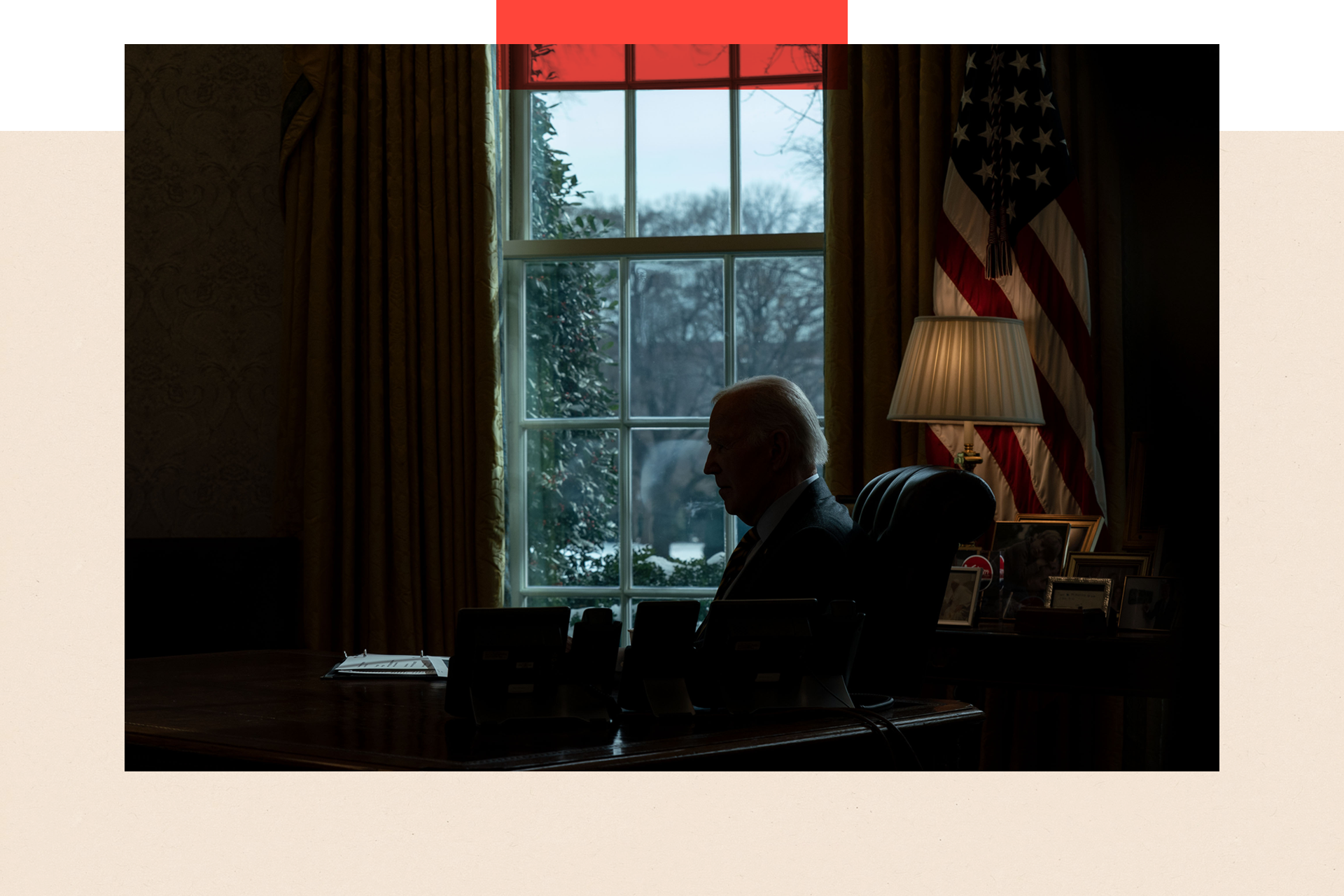 President Joe Biden receives a briefing at his desk in shadows