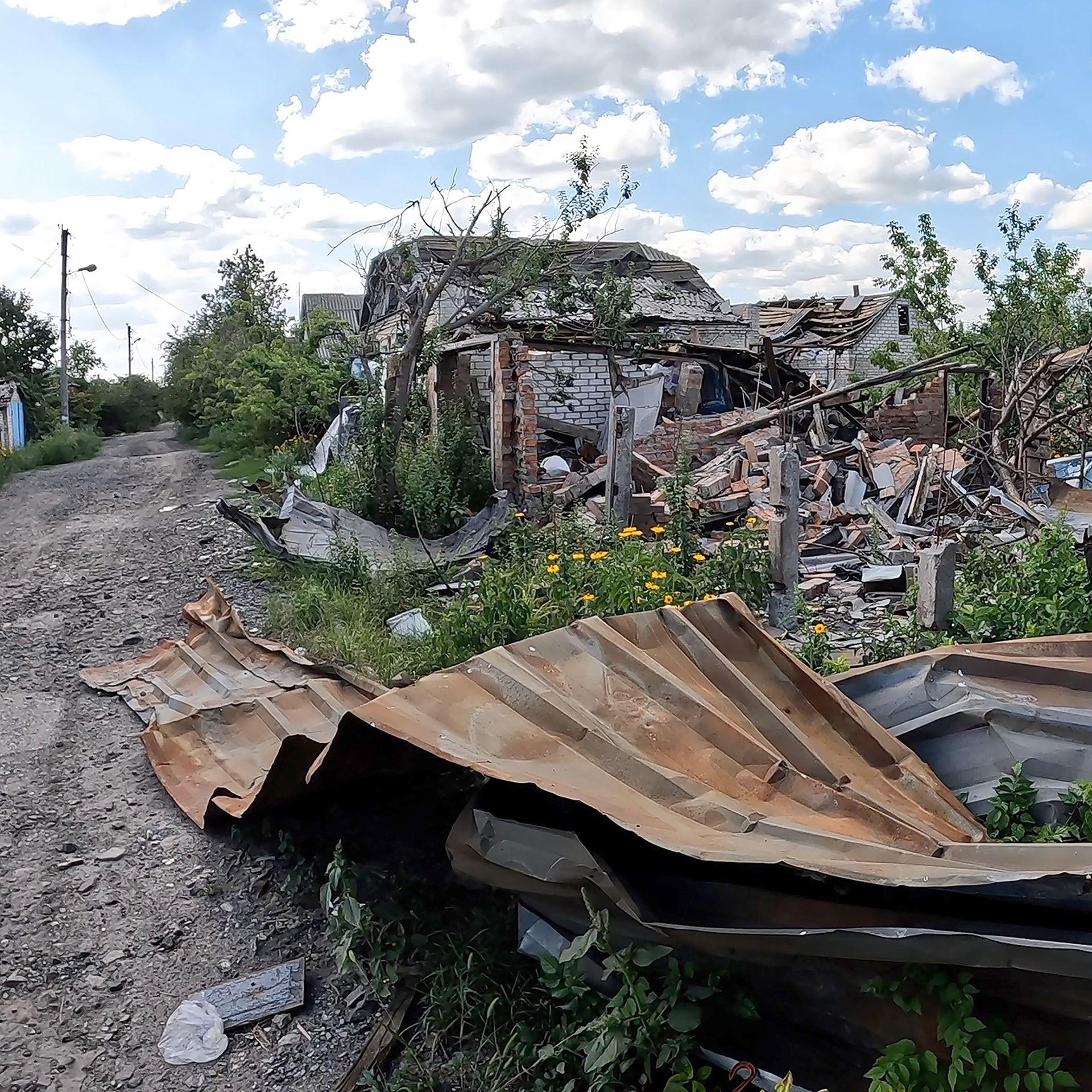 Ruined buildings in Lyman - a broken tin roof lies on the ground