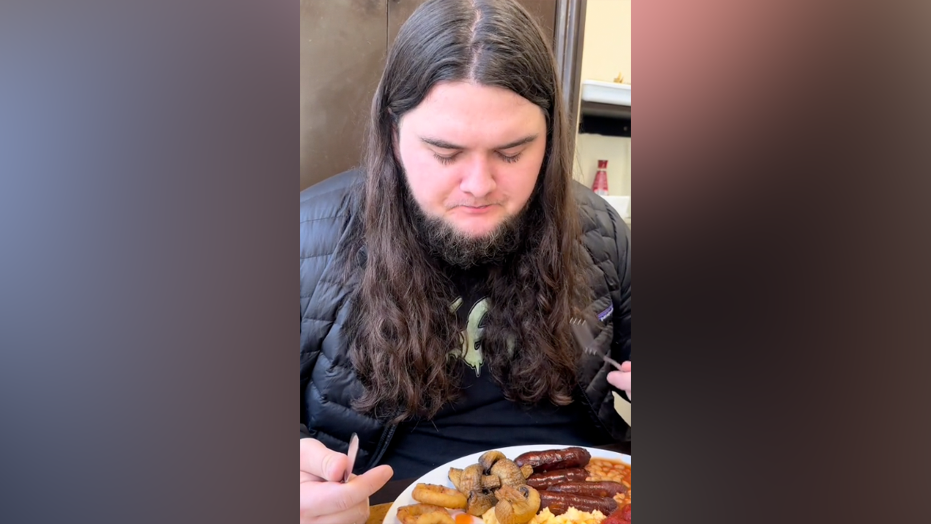 A man with long hair looks down at a full English breakfast