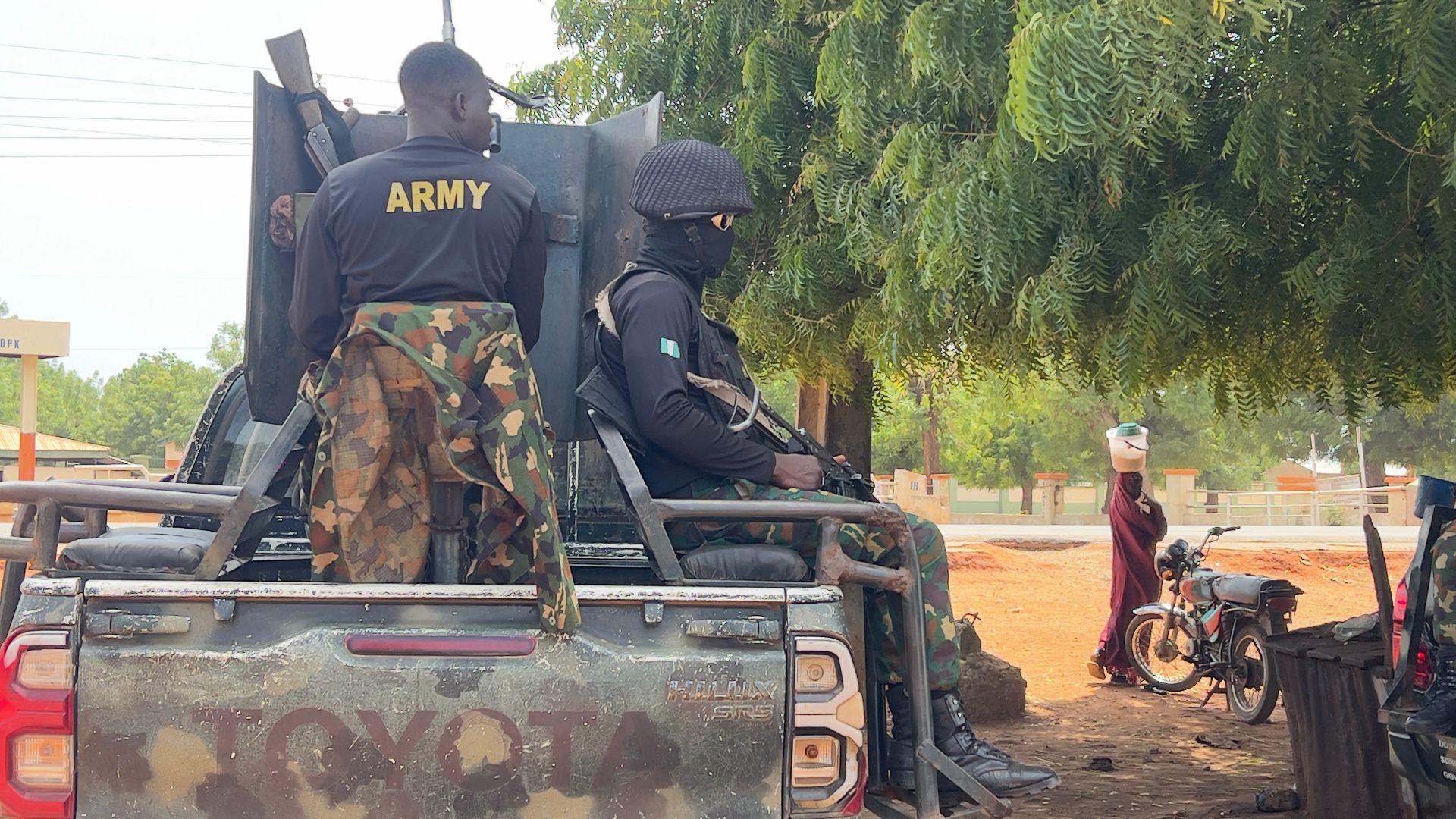 An service patrol truck, with 2 soldiers connected the backmost carrying guns. To the close of the vehicle, a pistillate balancing a bucket connected her caput walks past a motorcycle