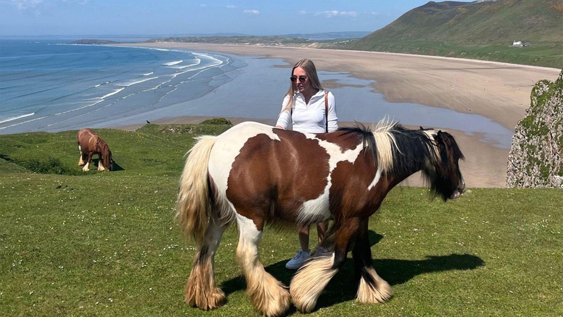Lucy gyda'r ceffylau gwyllt ar benrhyn Pen Pyrod yn ardal y Gwyr