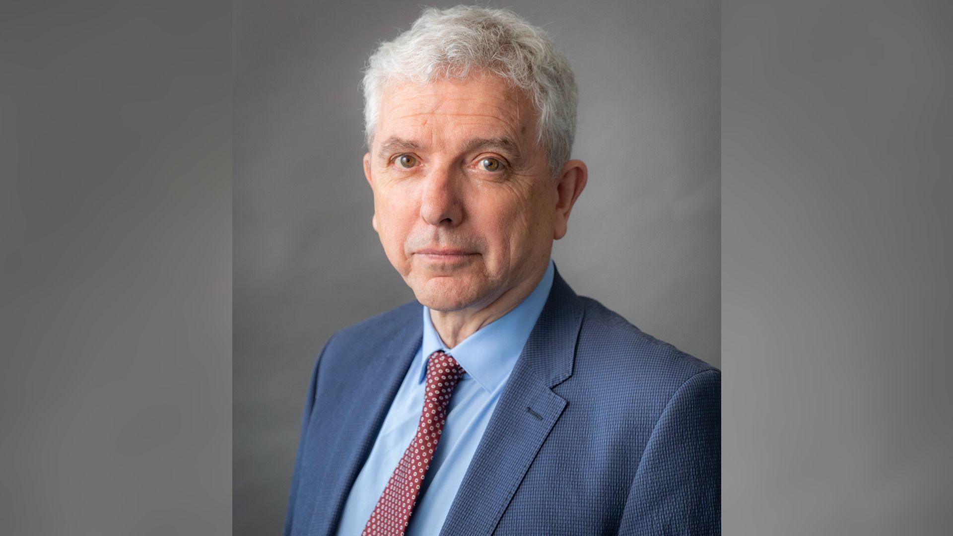 A headshot of Michael Gorman, the deputy leader of Cheshire East Council and the leader of the Independent Group. He has white hair and is wearing a dark blue suit, light blue shirt and red tie with cream spots. 