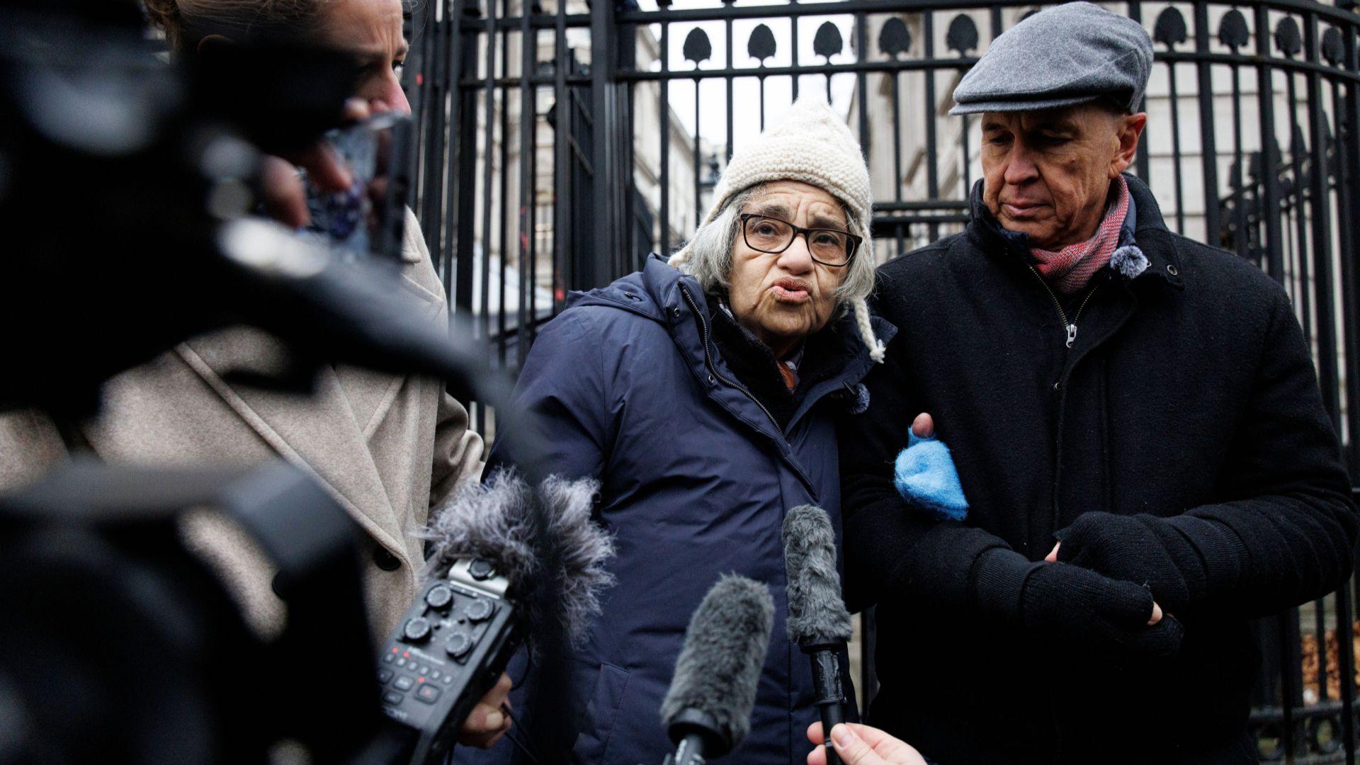 Laila Soueif, an elderly woman, is supported by two people either side of her as she gives a statement to the members of media outside the gates of Downing Street.