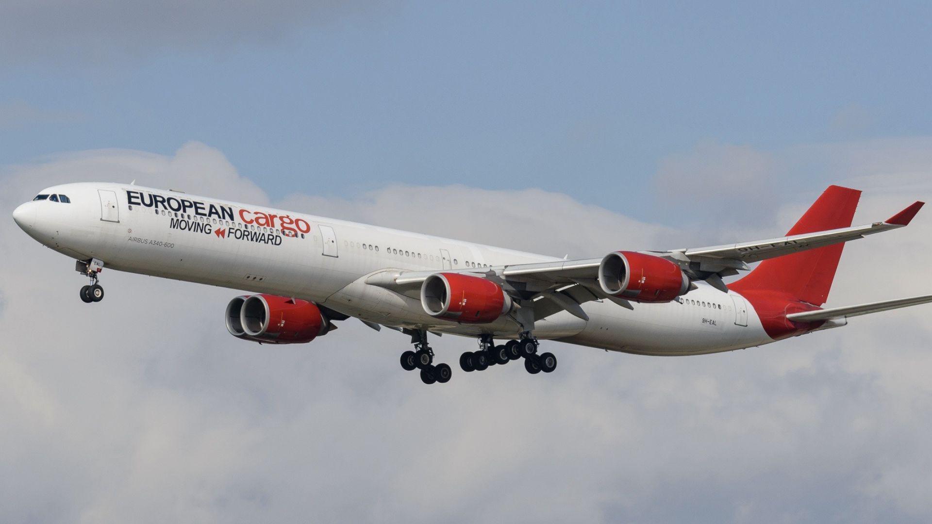 A European Cargo plane in flight, with its white body, red tail fin and red engines.