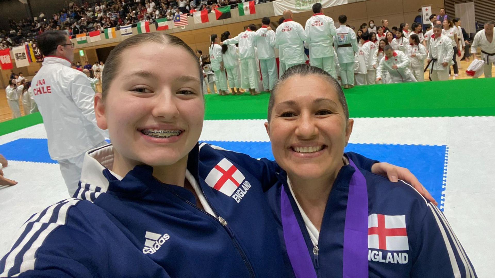 Bianca and Cyra Webb wearing matching navy Adidas tracksuits with the England flag on them. Bianca also has a medal around her neck.