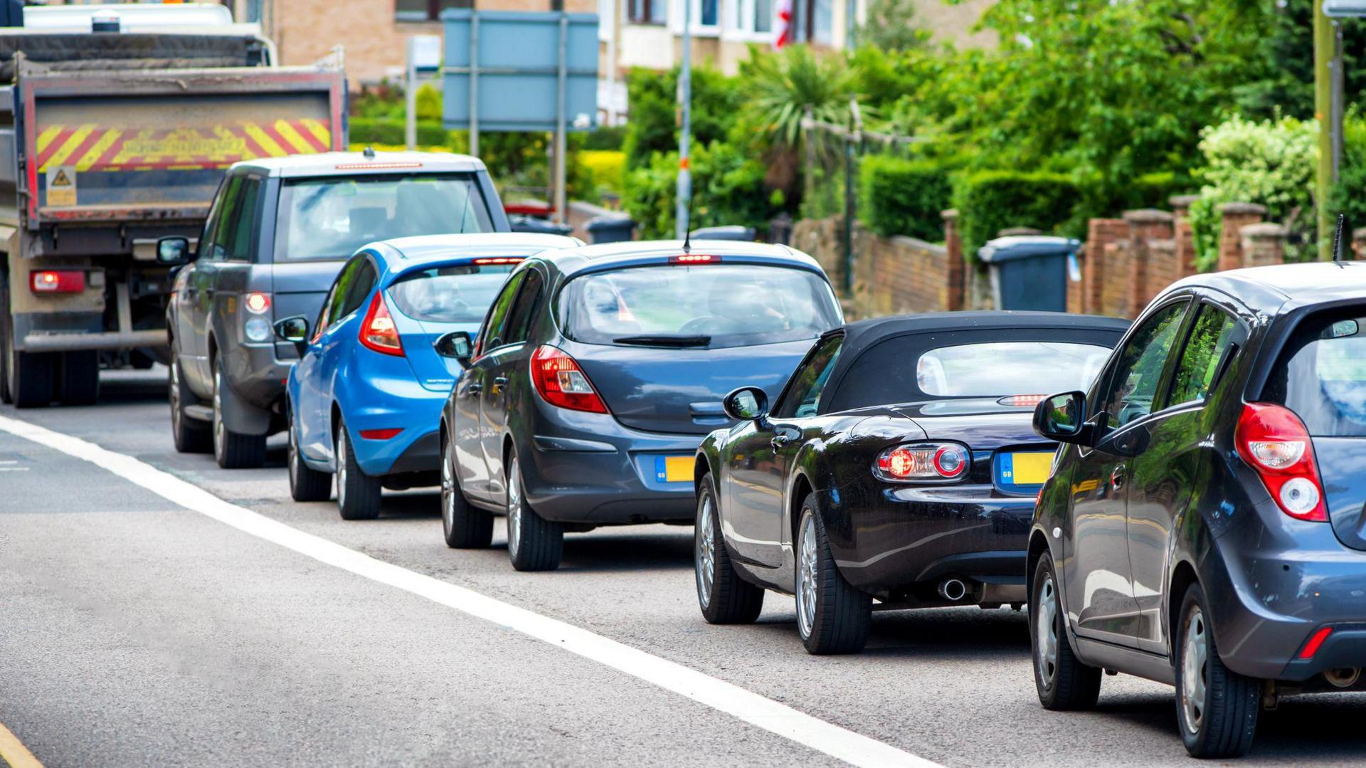 A queue of cars form traffic next to a bus lane 