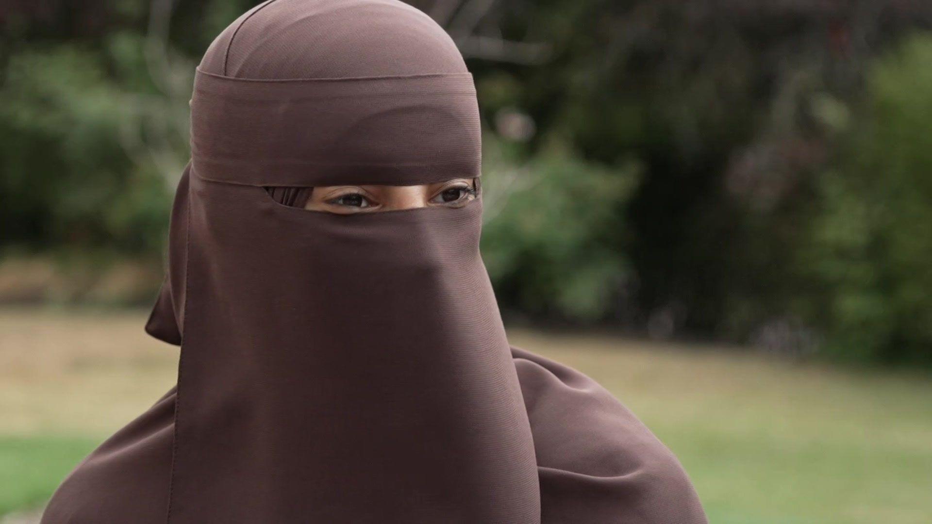 Salsabil in a brown niqab and headscarf, with greenery behind her
