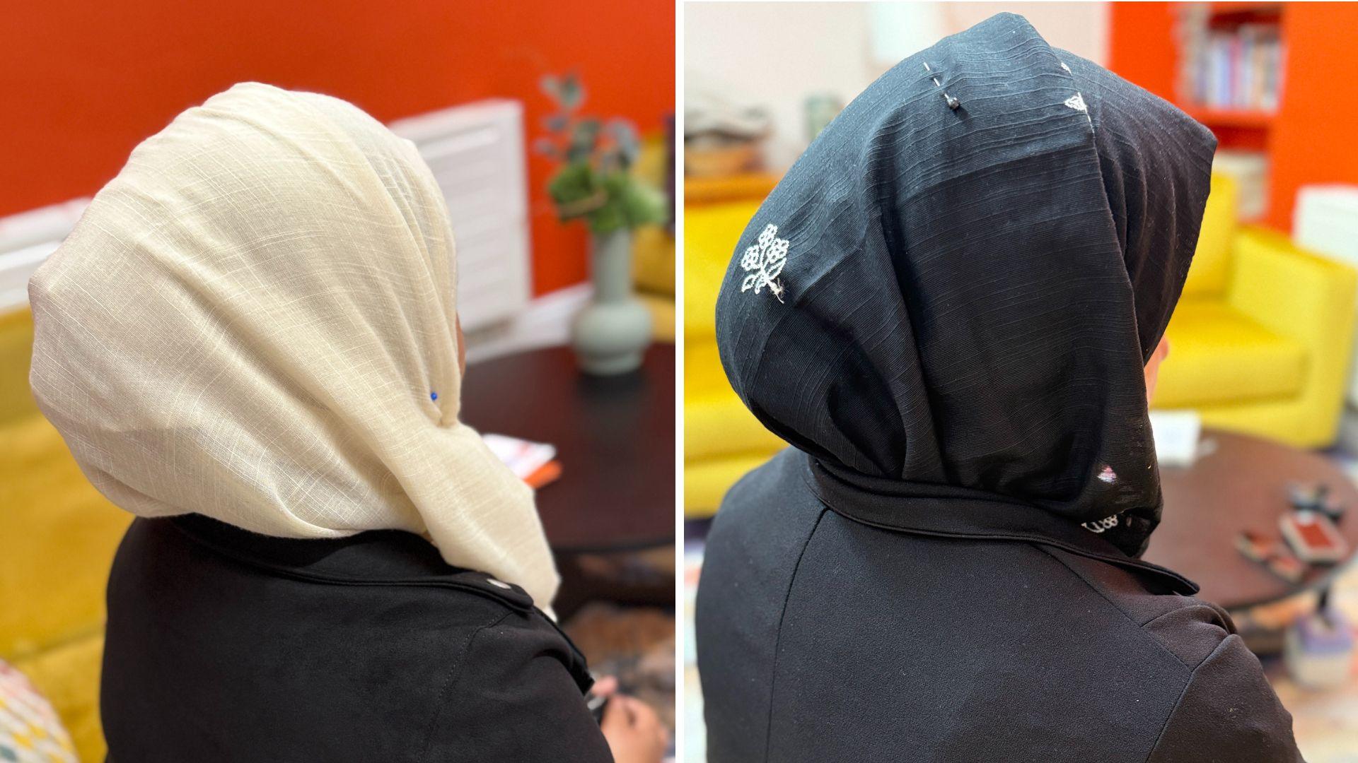 The backs of two women's heads. One is wearing a cream coloured hajib and the other a black one with a white flower motif.