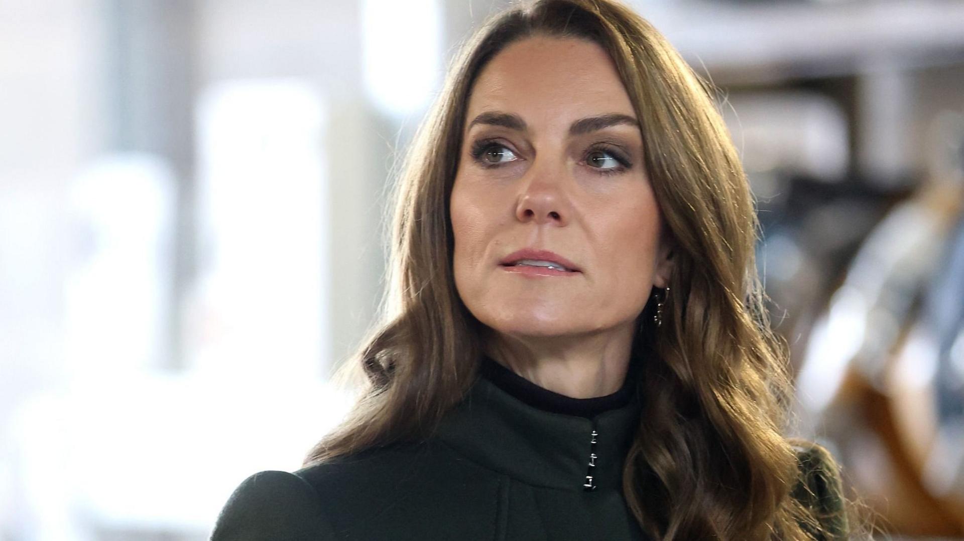 The Princess of Wales looks off into the distance. She's wearing a dark green coat.