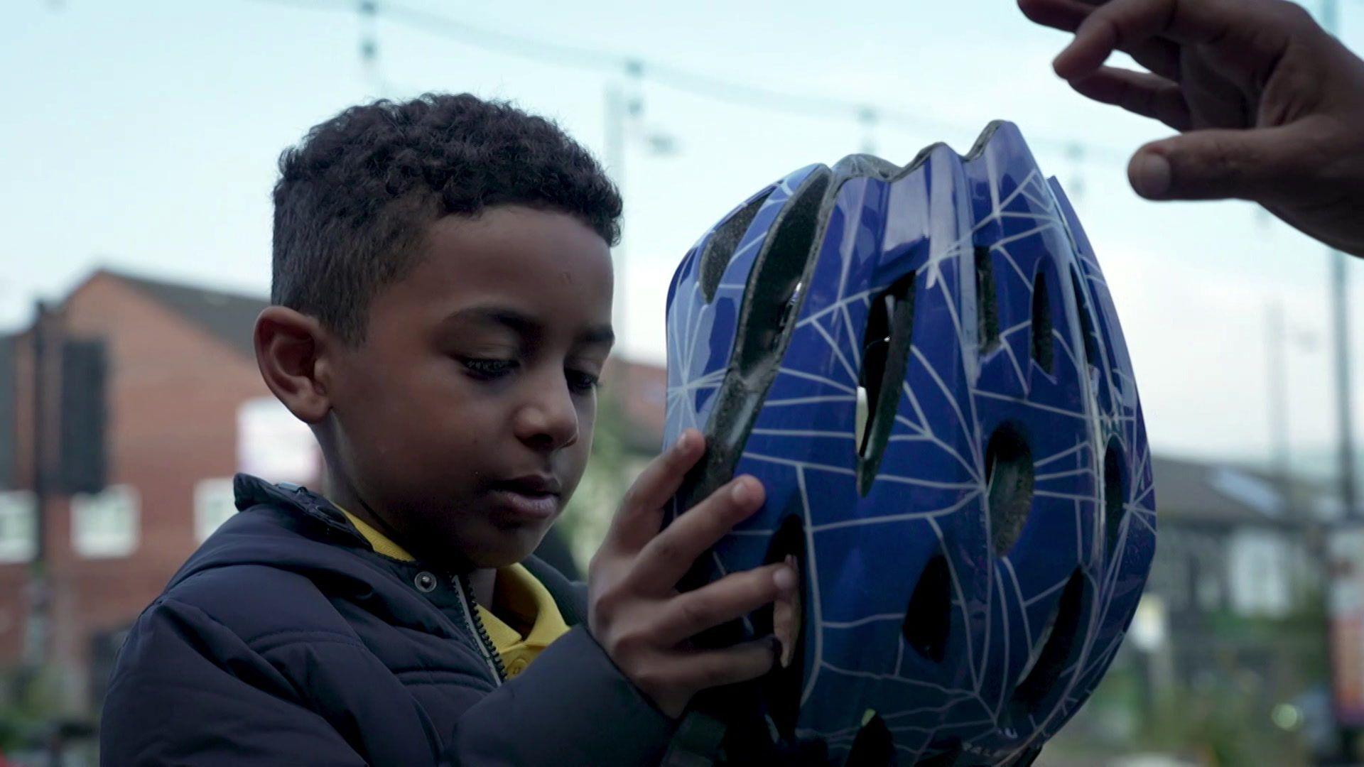 Boy putting on a cycling helmet to help keep safe