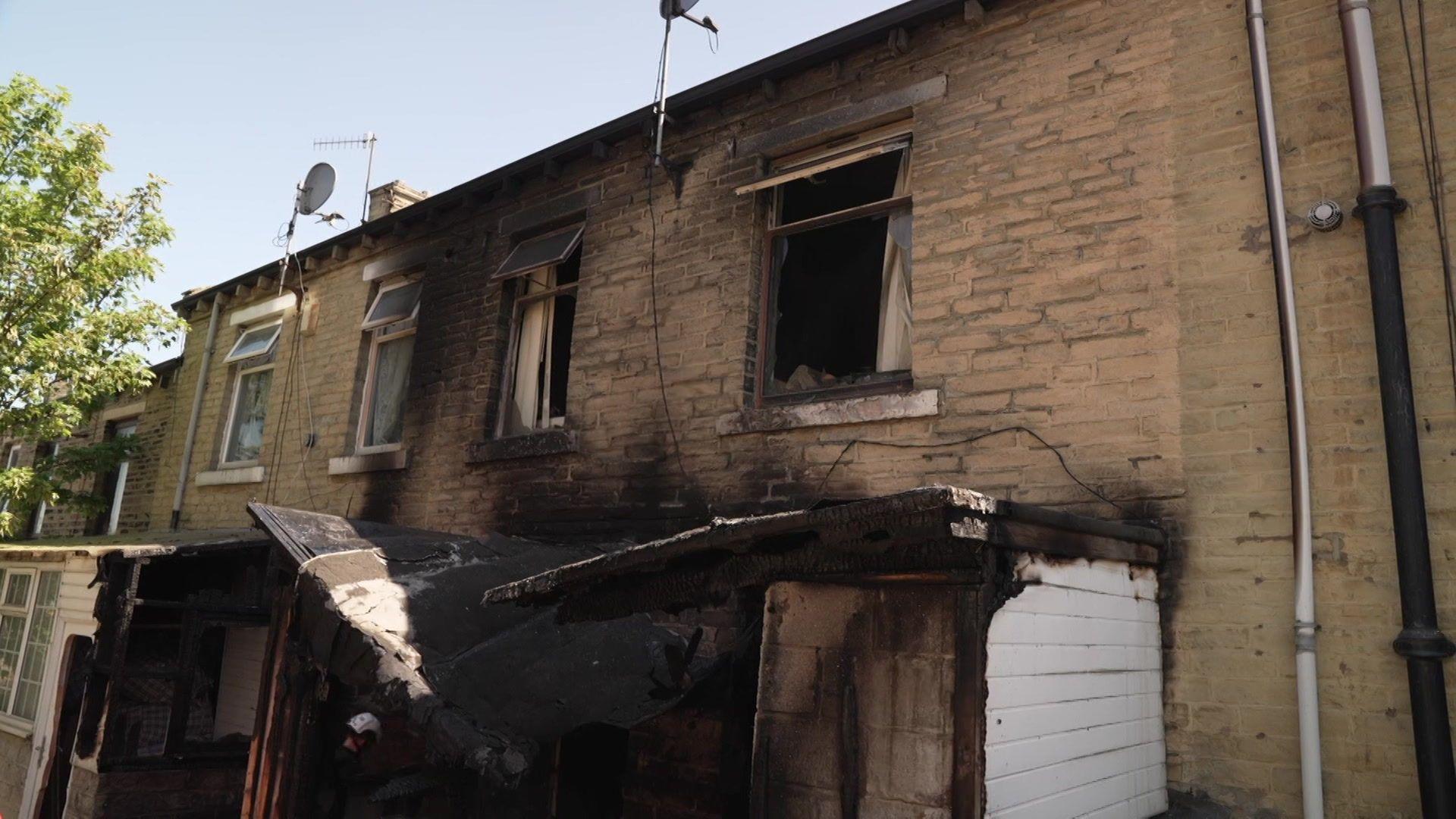 A fire-damaged building, with a broken rood section and smashed windows.