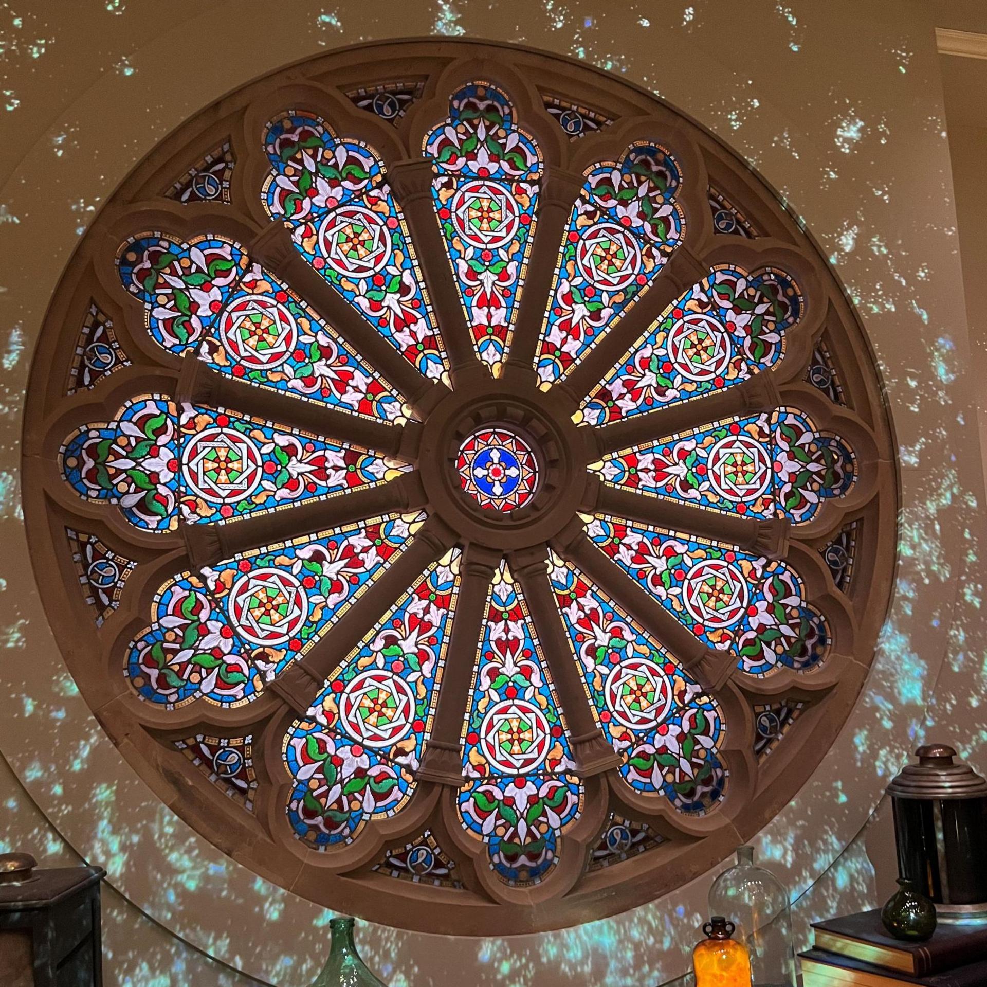 Rose Window is round and highly decorative. It features stained glass of colours of red, pink, green and blue.