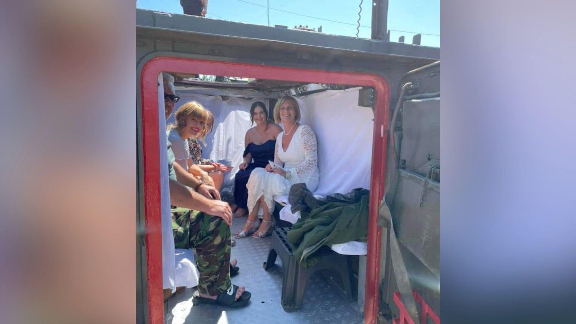 Several people including a bride sitting inside an armoured personnel carrier