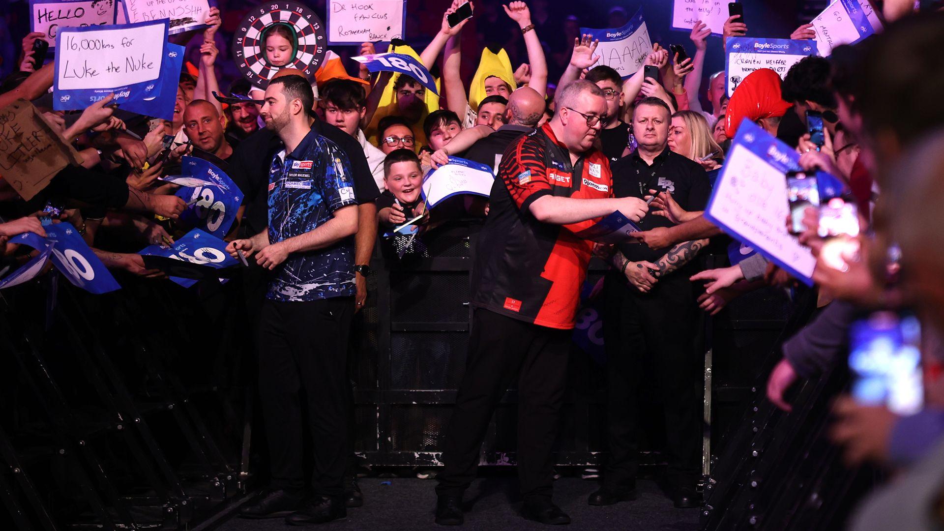 Luke Humphries and Stephen Bunting sign autographs ahead of walking to the stage