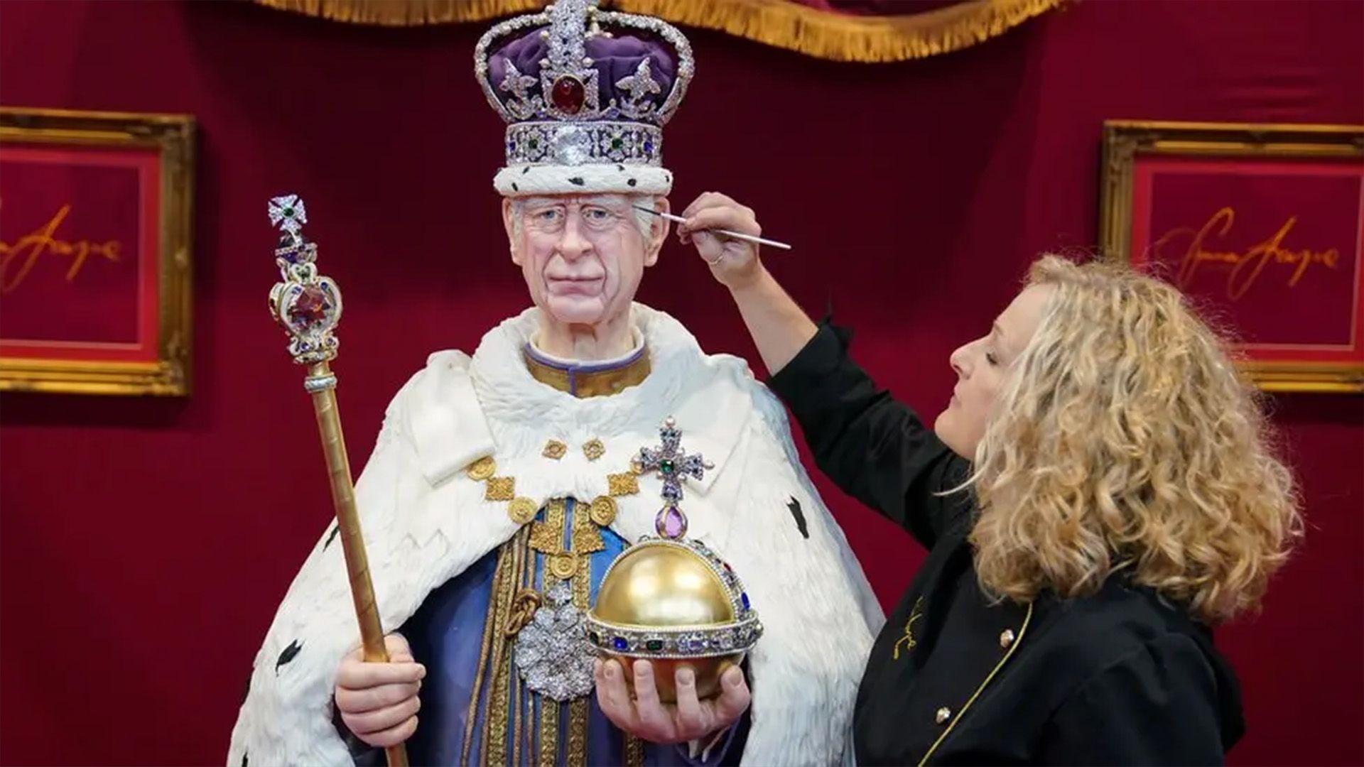 Emma Jayne paints on the King's face which is made of cake. It looks very lifelike. He is wearing regalia including the crown jewels and a white cloak. 