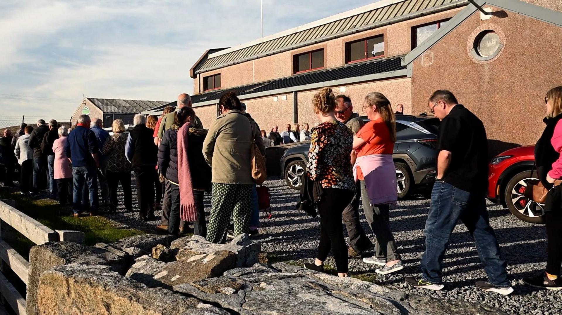 Daoine a' feitheamh taobh a-muigh Talla a' Chinn a Deas