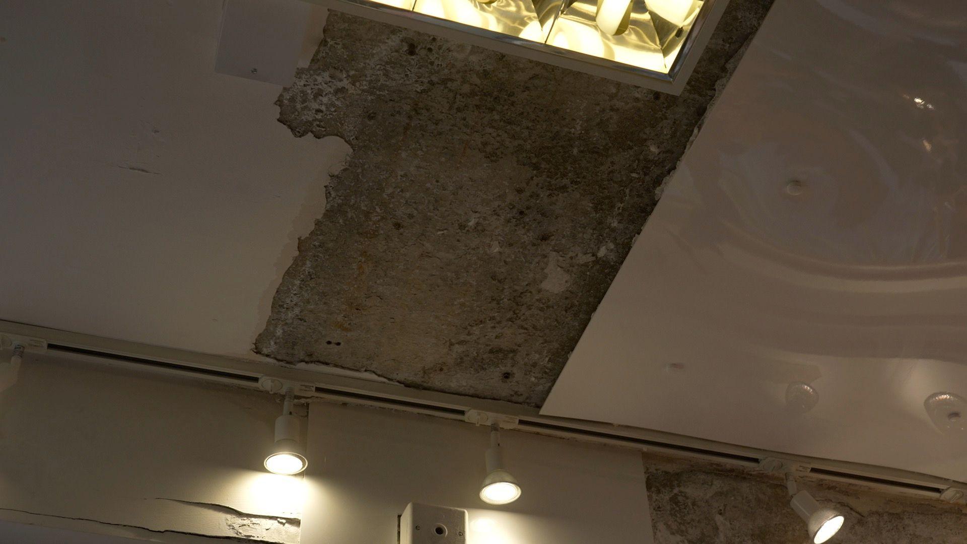 A grey area of damage on Deirdre's ceiling. The damage is surrounded by lights on either side.