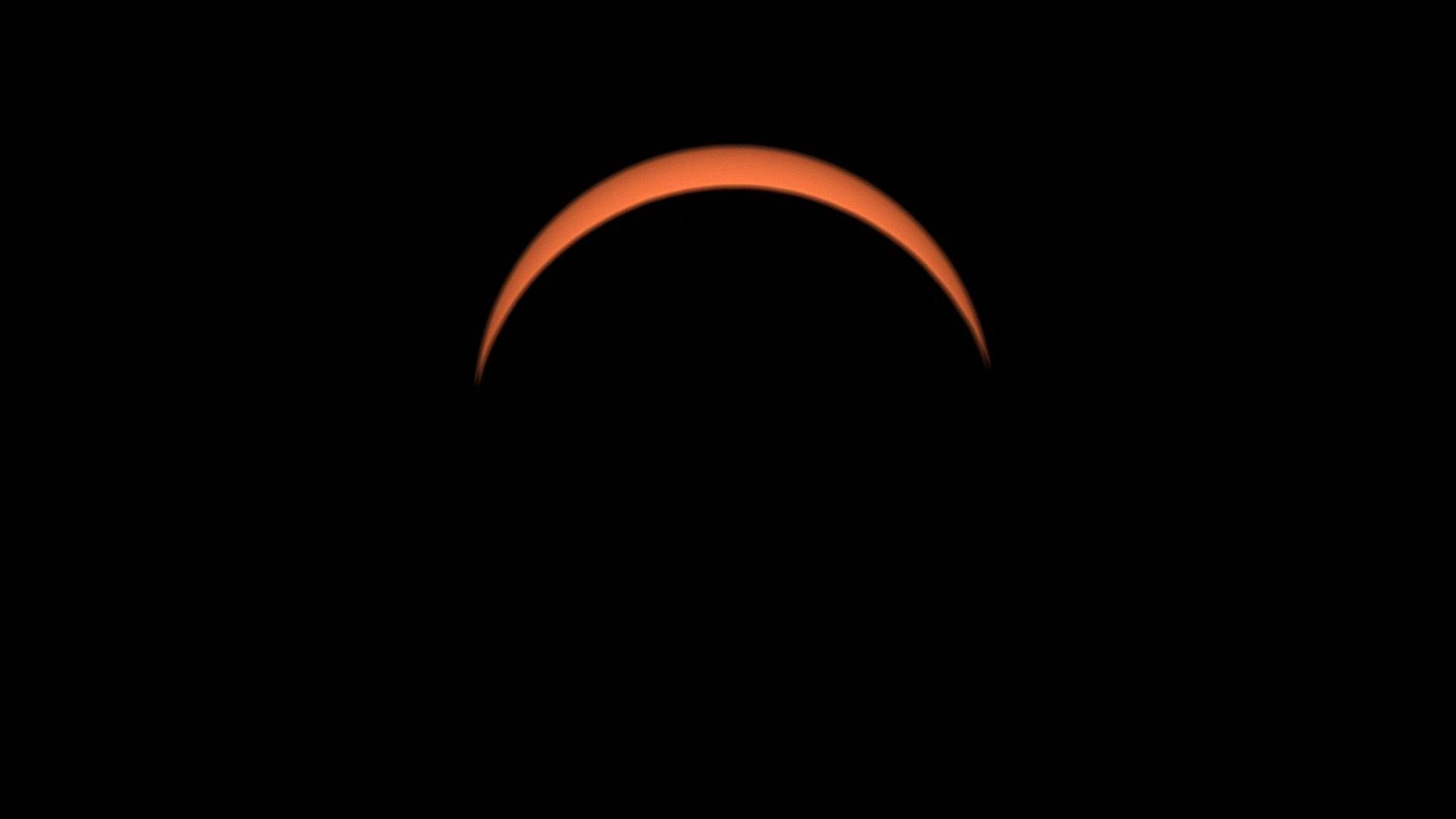 A view of the sun, which has been mostly covered. All that can be seen is an orange semi-circle.