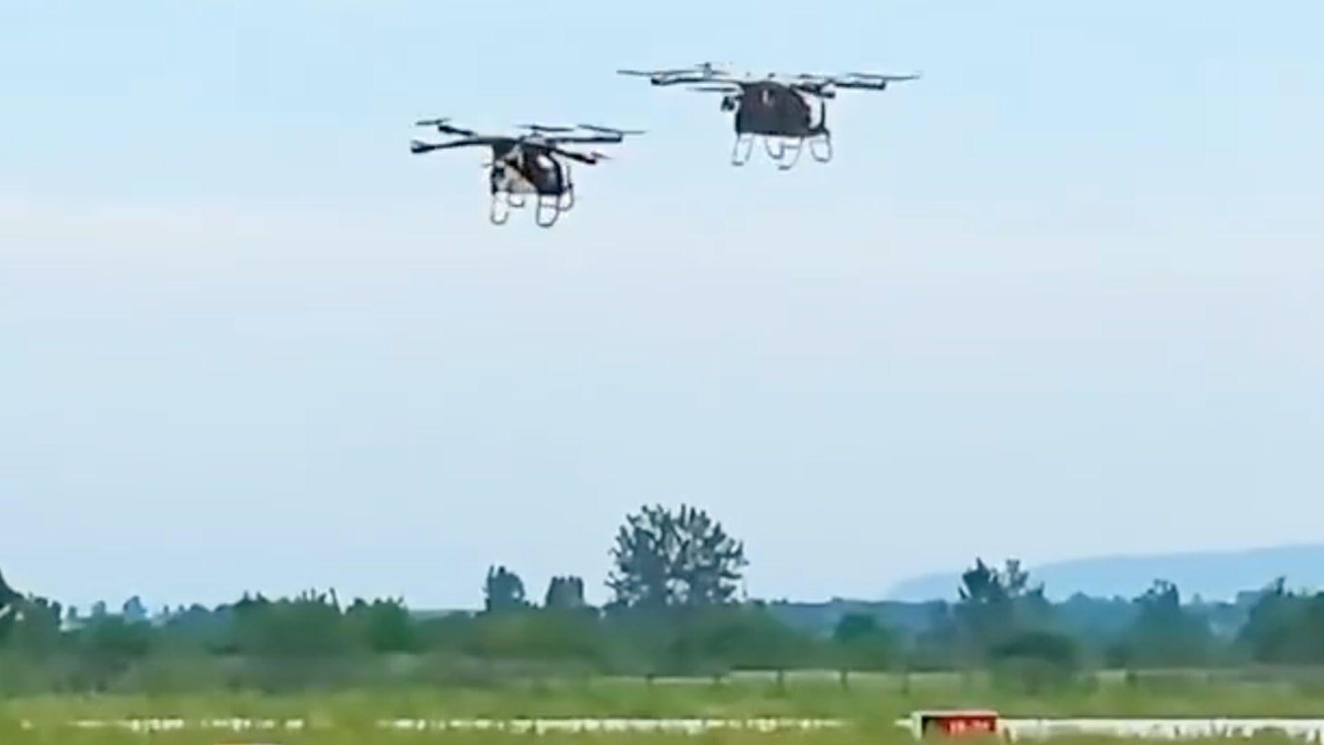 Two flying cars, each with four sets of propellors, flying close to each other in a still from a social media video