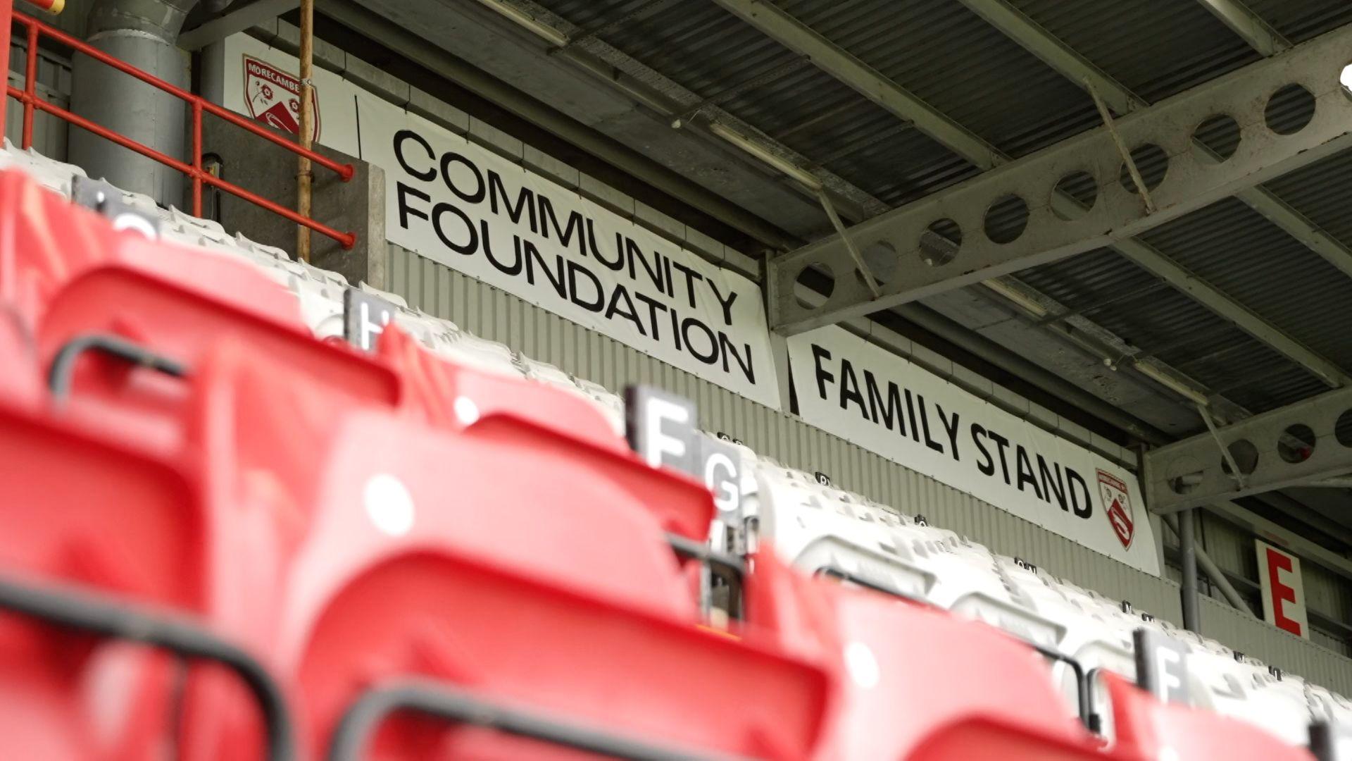 Signs reading Community Foundation and Family Stand adorn the back of a stand at Morecambe's Stadium