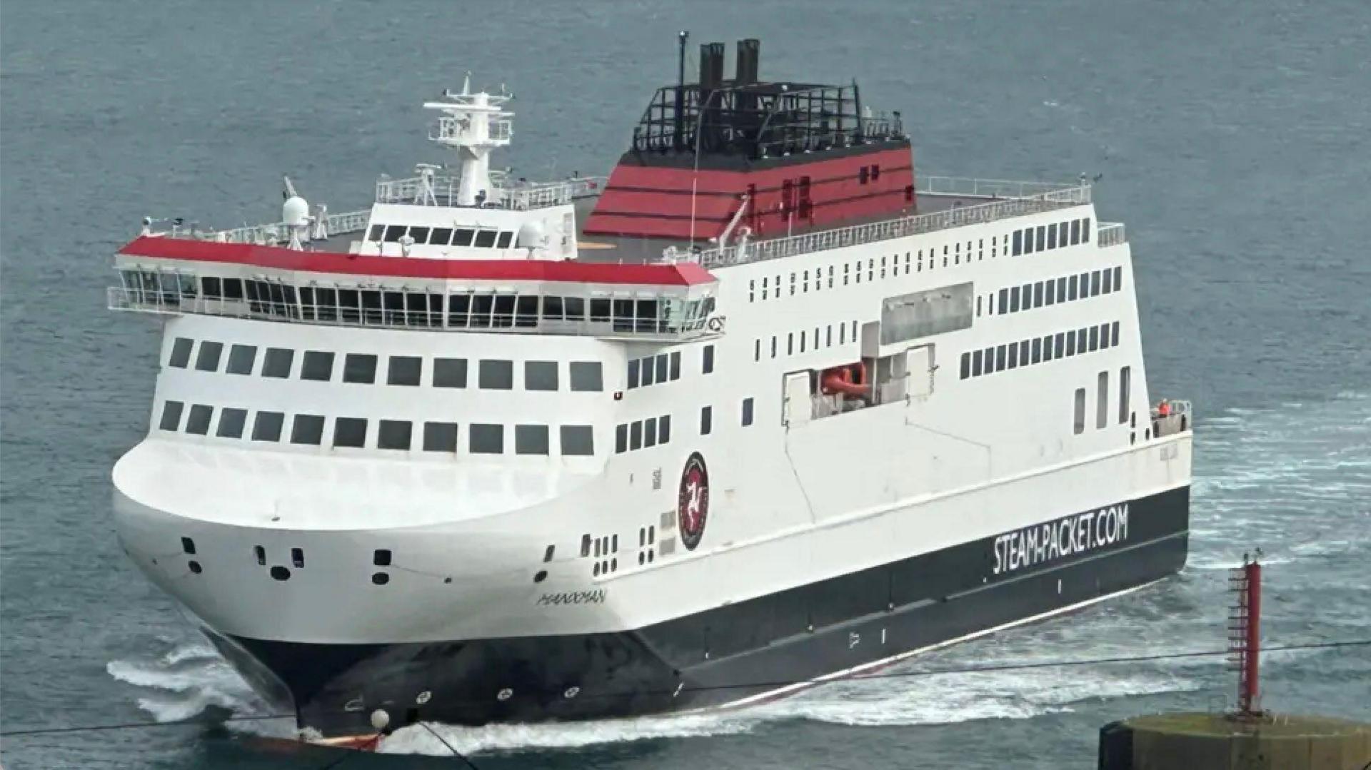 The Manxman sailing towards Douglas in calm waters. It is painted in the Steam Packet's livery of black, white and red and has the company's logo on the side at the front and the words STEAM.PACKET.COM further towards the back.