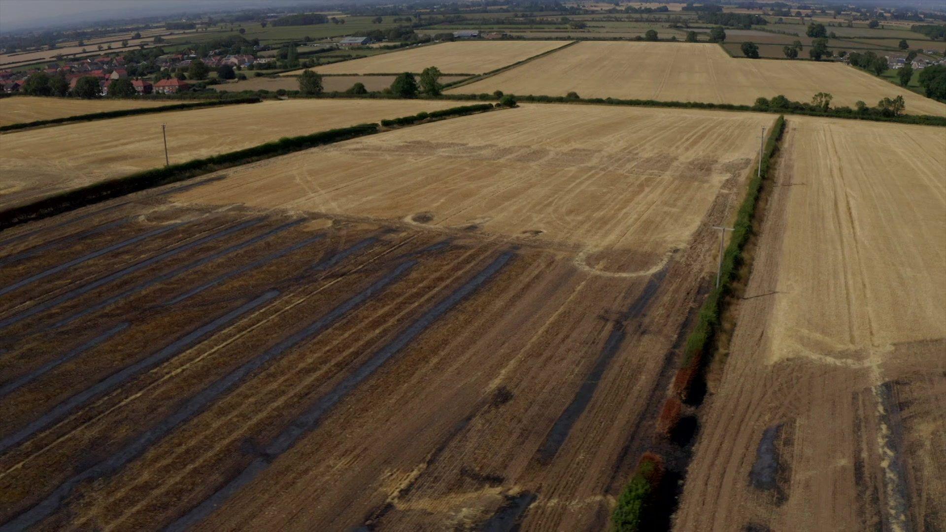 Light brown crop fields with brown and black scarring from fire.