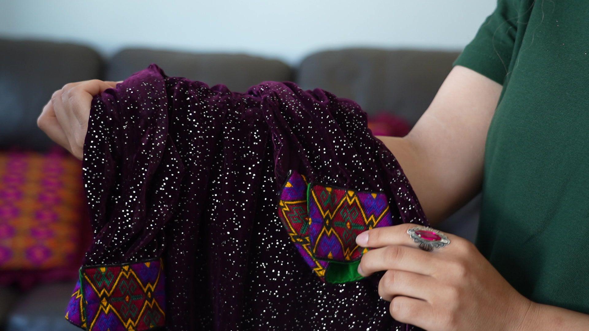 Pervin is holding a purple dress that has intricate patterns