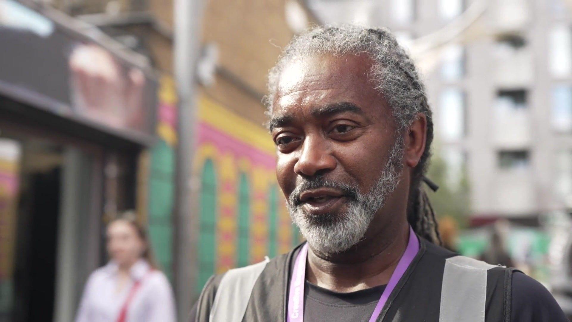 Barrington Todd wears a black t-shirt and a purple lanyard. He has a beard.