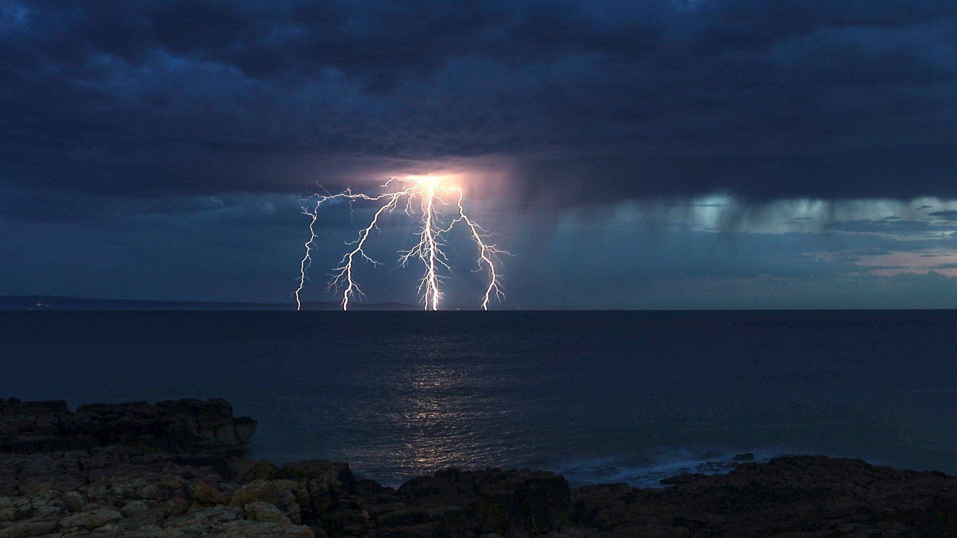 Fork lightning over the sea with dark clouds at night