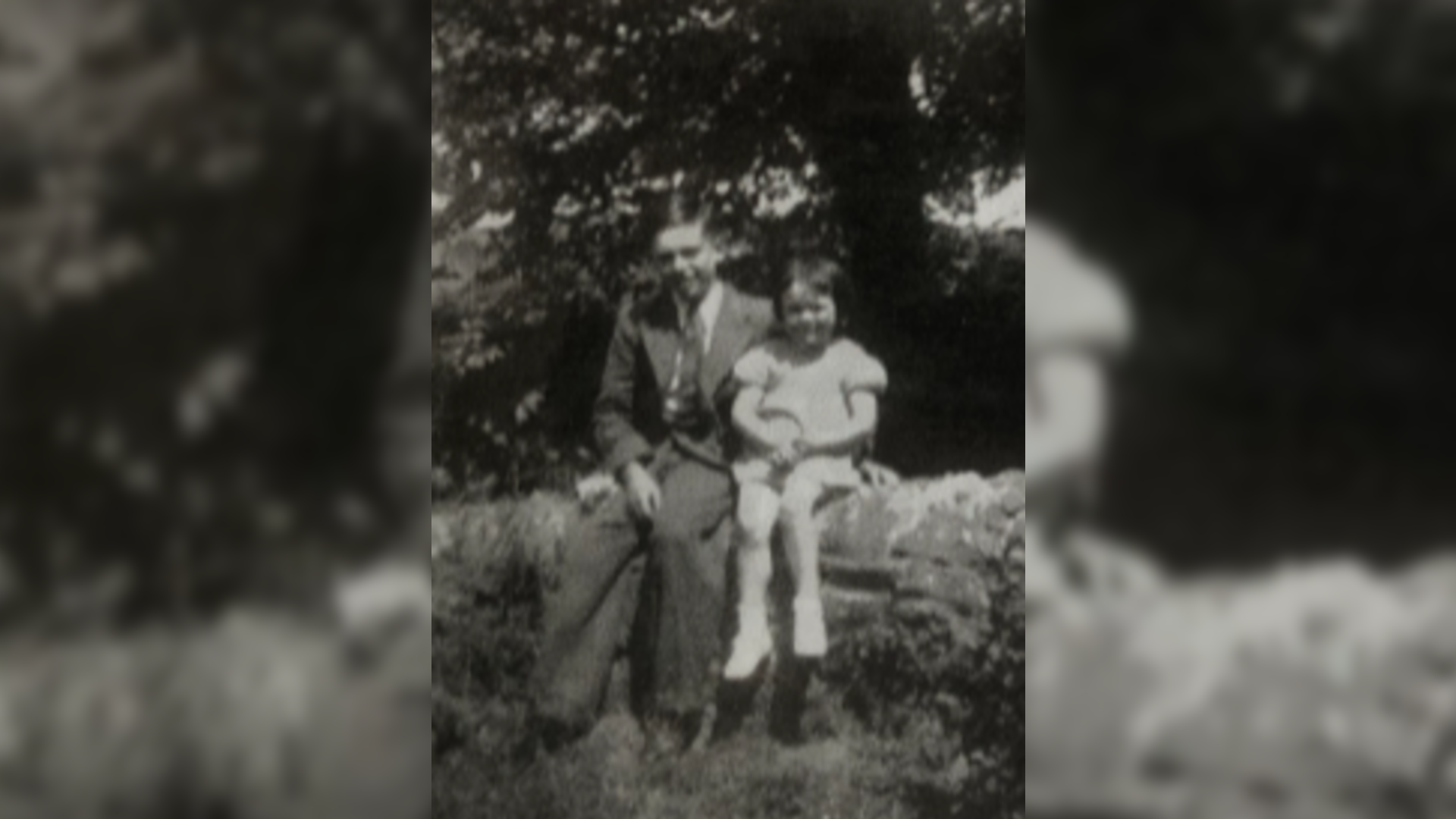 A portrait image of Barry sitting on a wall his his arm around his younger sister Patricia.