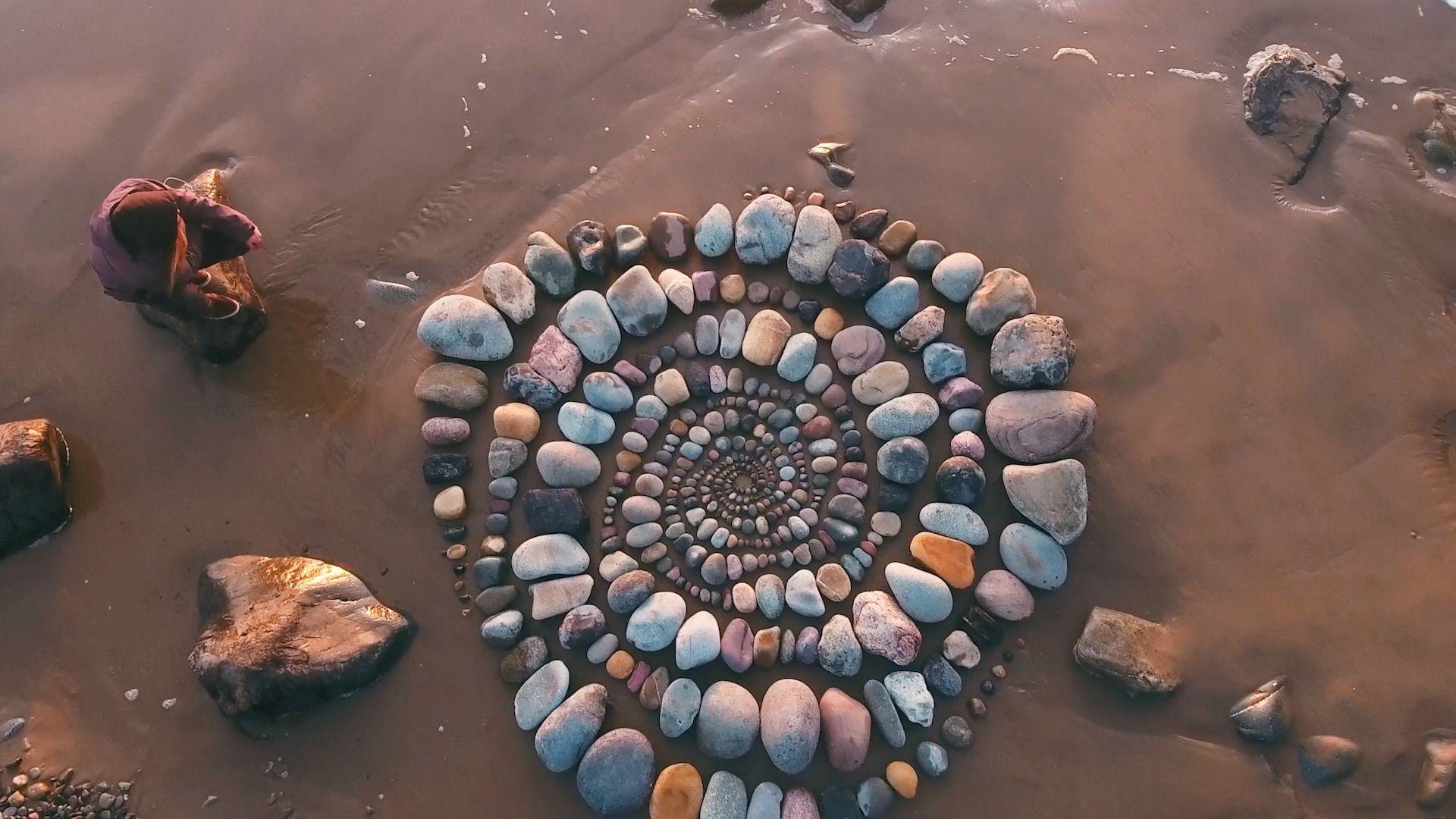 Rocks of various colours in a circular pattern on a beach