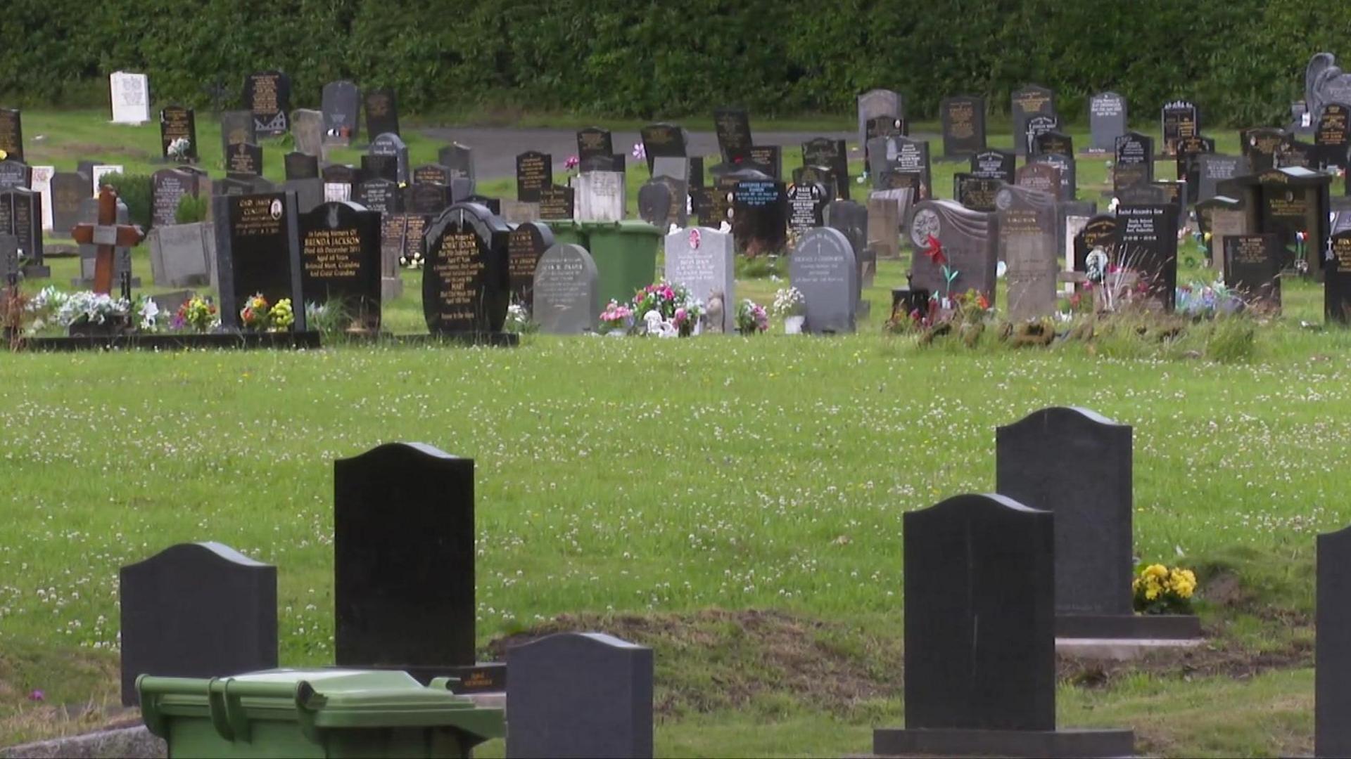 Rows of gravestones in Rawtenstall Cemetery. Many of the graves are adorned with flowers.