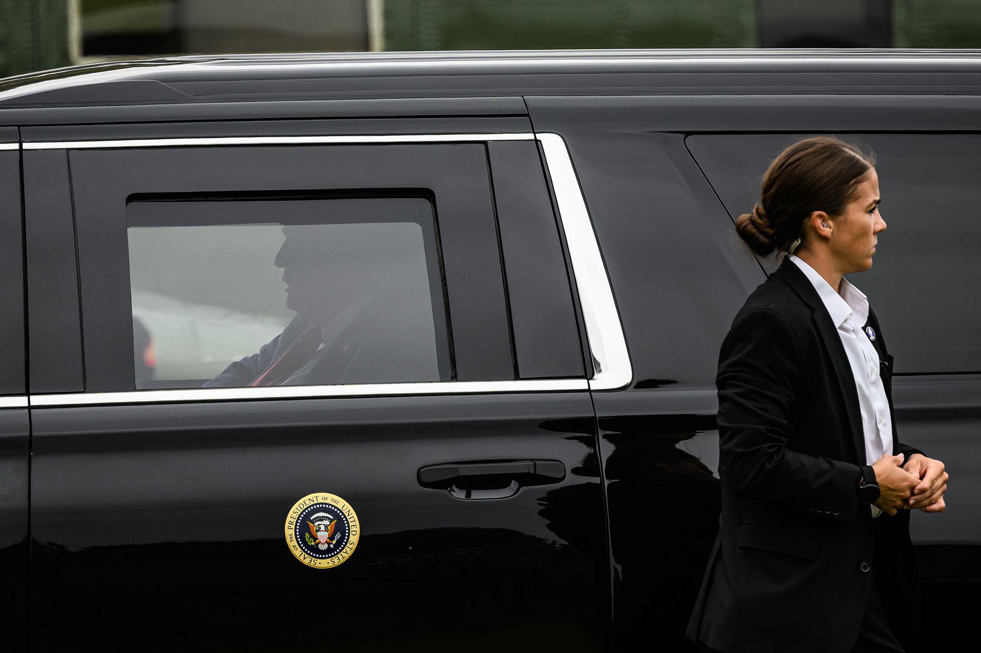 Profile of US President Donald Trump who can be seen sitting in a car after arriving at Chequers, with a female security guard standing by the side