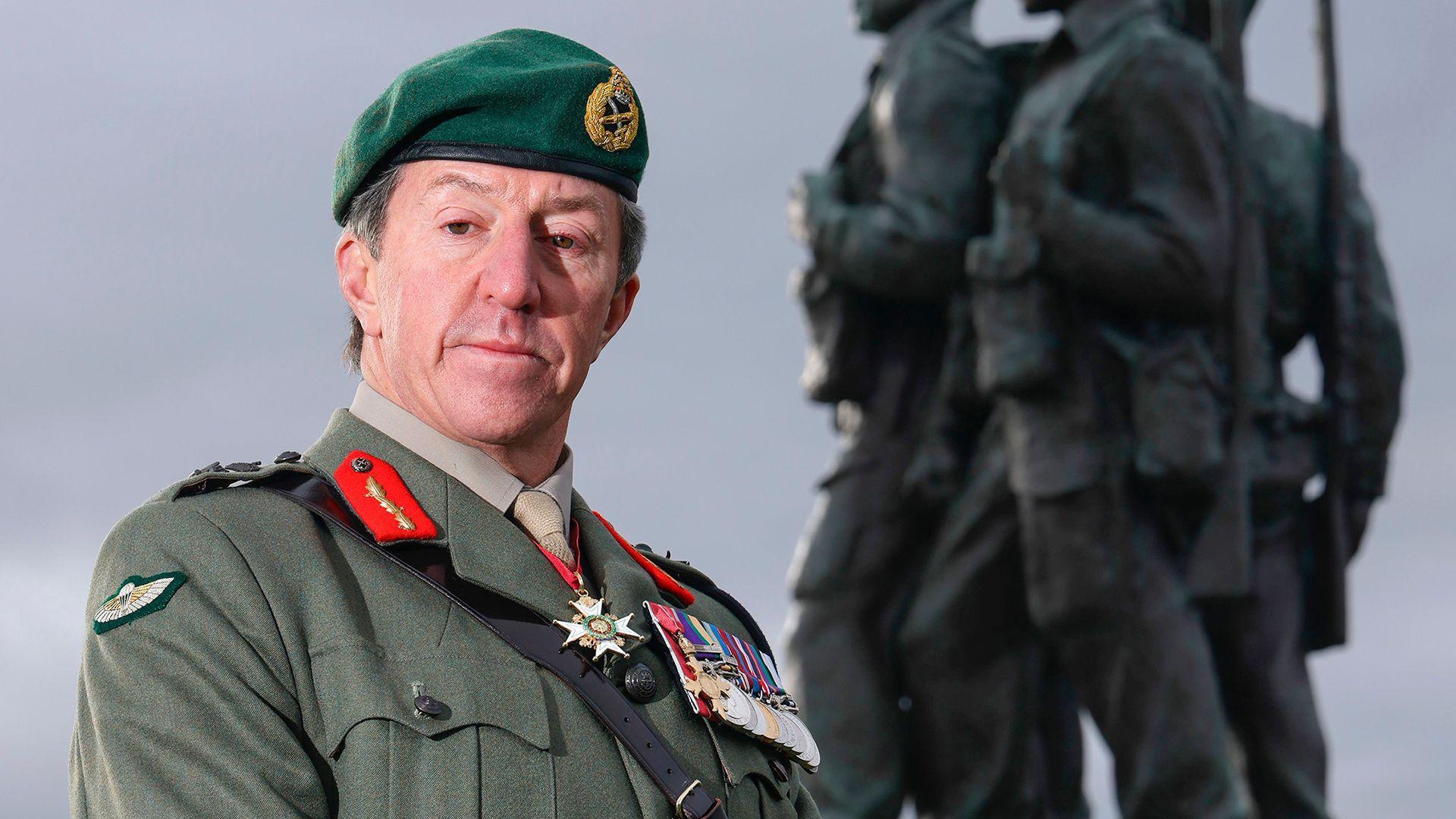 Gen Sir Gwyn Jenkins, in military uniform with medals on his chest, standing in front of the Commando Memorial in Locharber in the Scottish Highlands