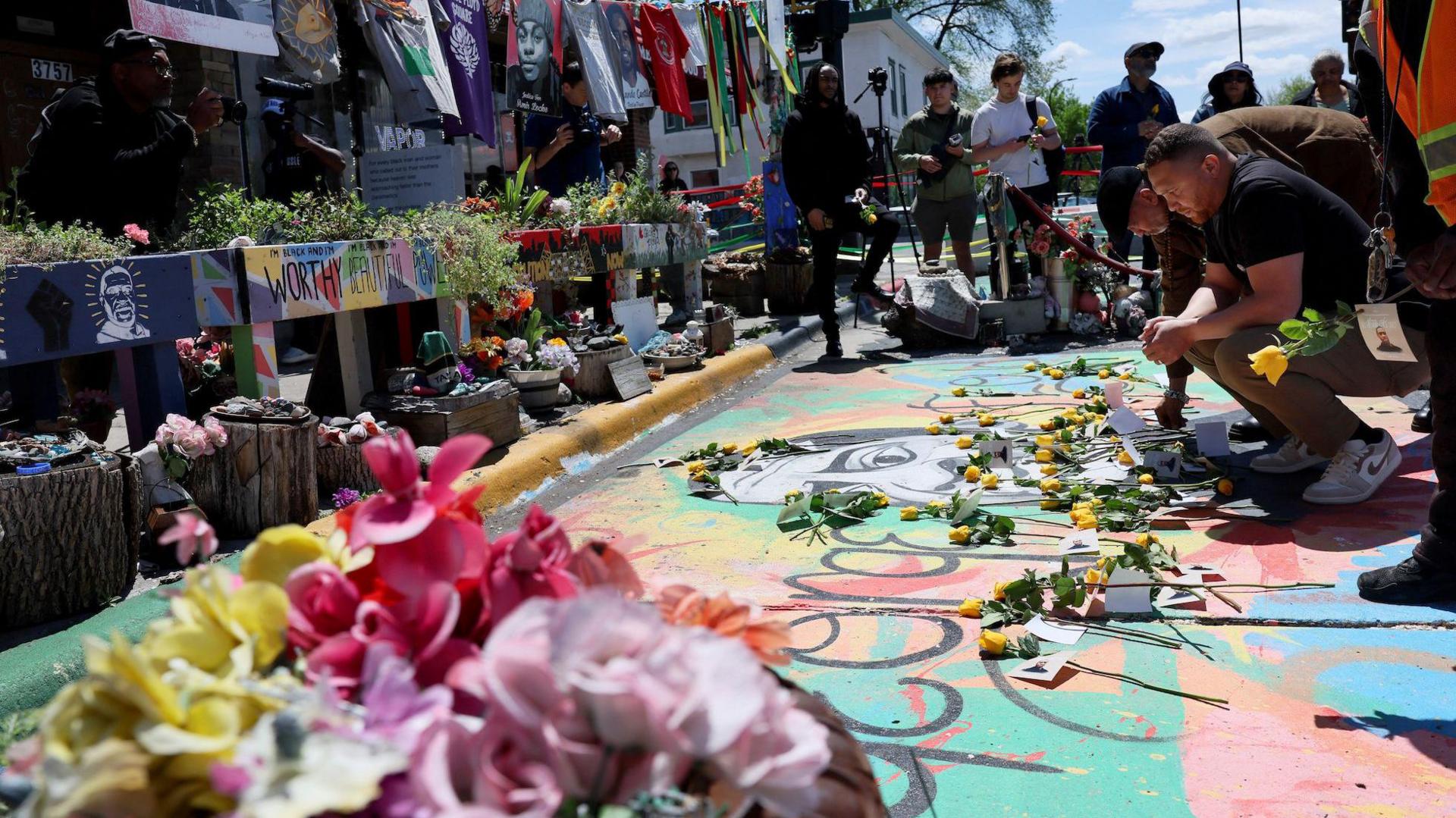 A man lays yellow roses at a memorial for George Floyd