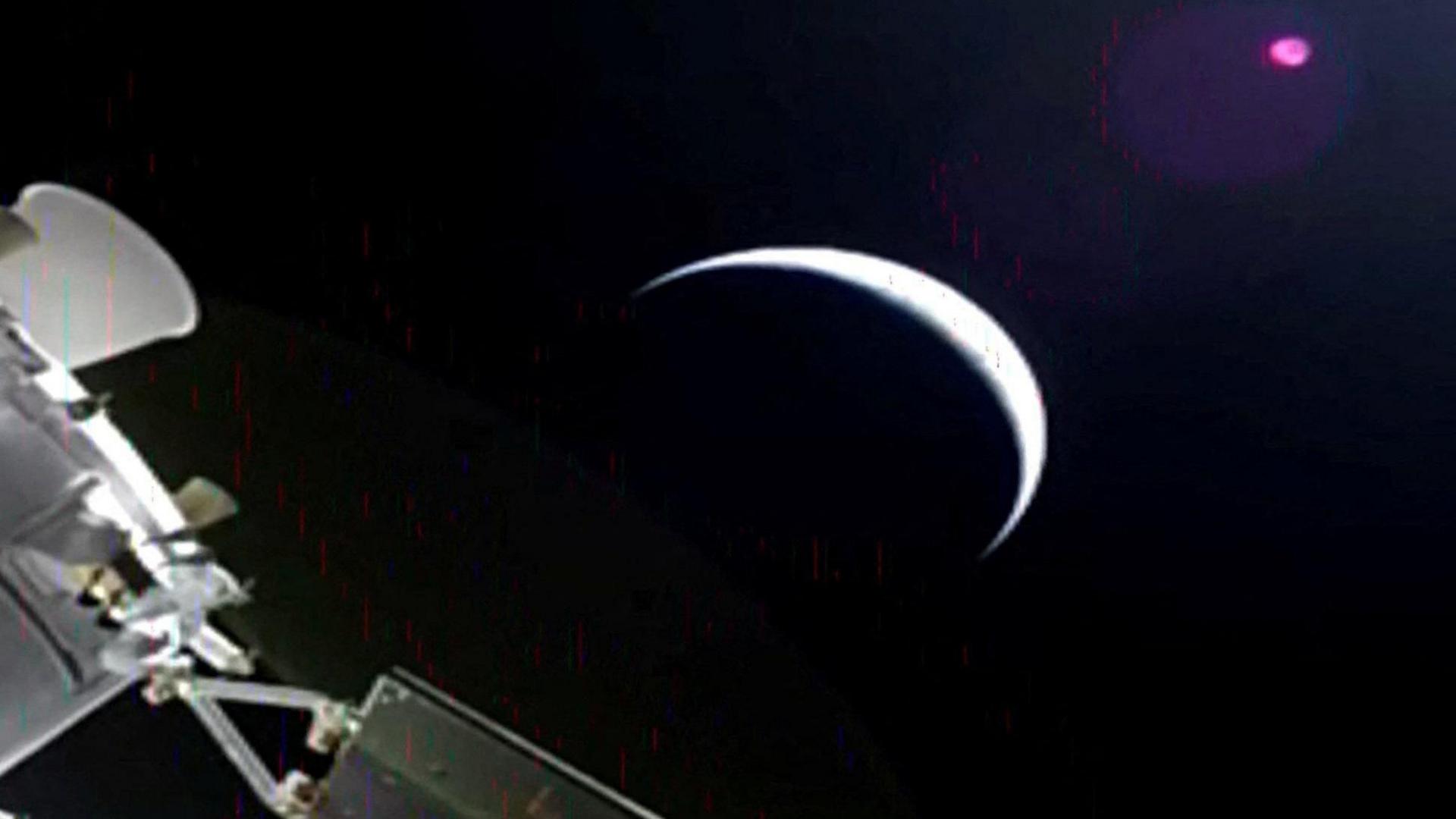 A sliver of the moon and parts of the orion spacecraft off to the side.