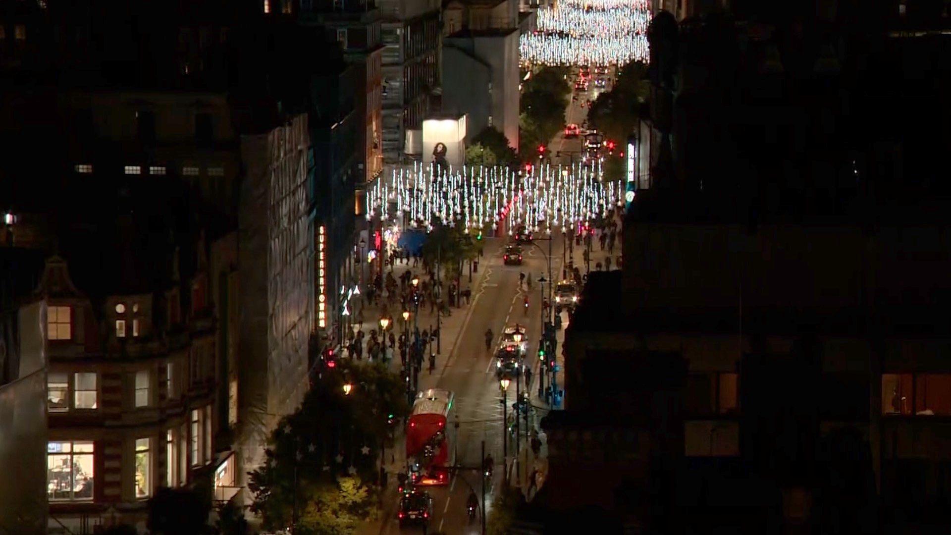 Aerial view of Oxford Street in central London showing the twinkly stars over the street with a double decker bus and cars driving with their lights on