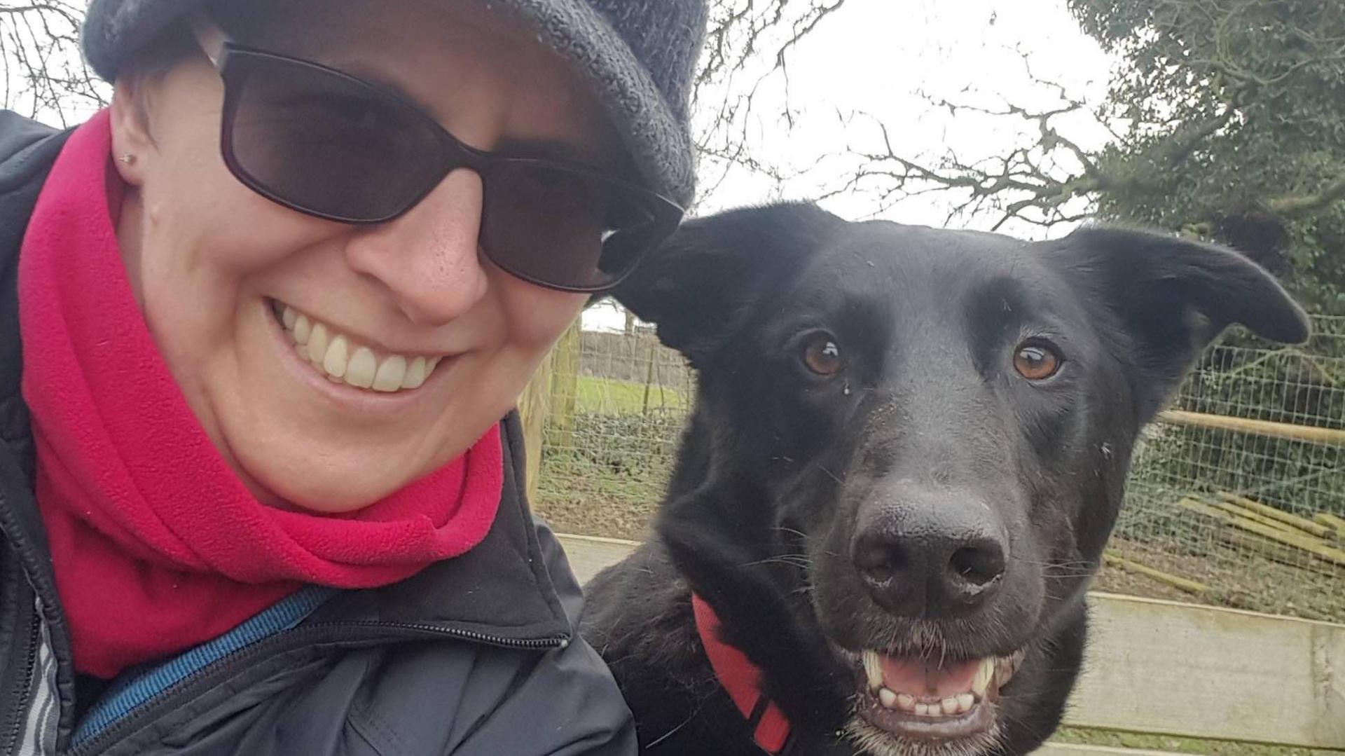 Lorna Vyse and Wilbur. They are both looking at the camera. Lorna is smiling and wearing sunglasses and a red scarf. Wilbur has his mouth open, and his ears are alert