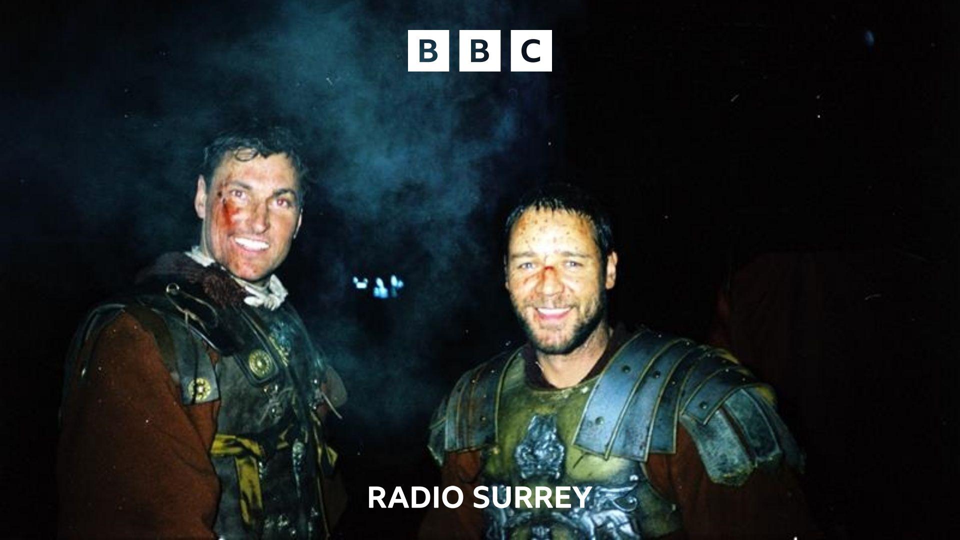 Extra Andy Bowden stands with Russell Crowe. Both are smiling at the camera and dressed in Roman costumes.