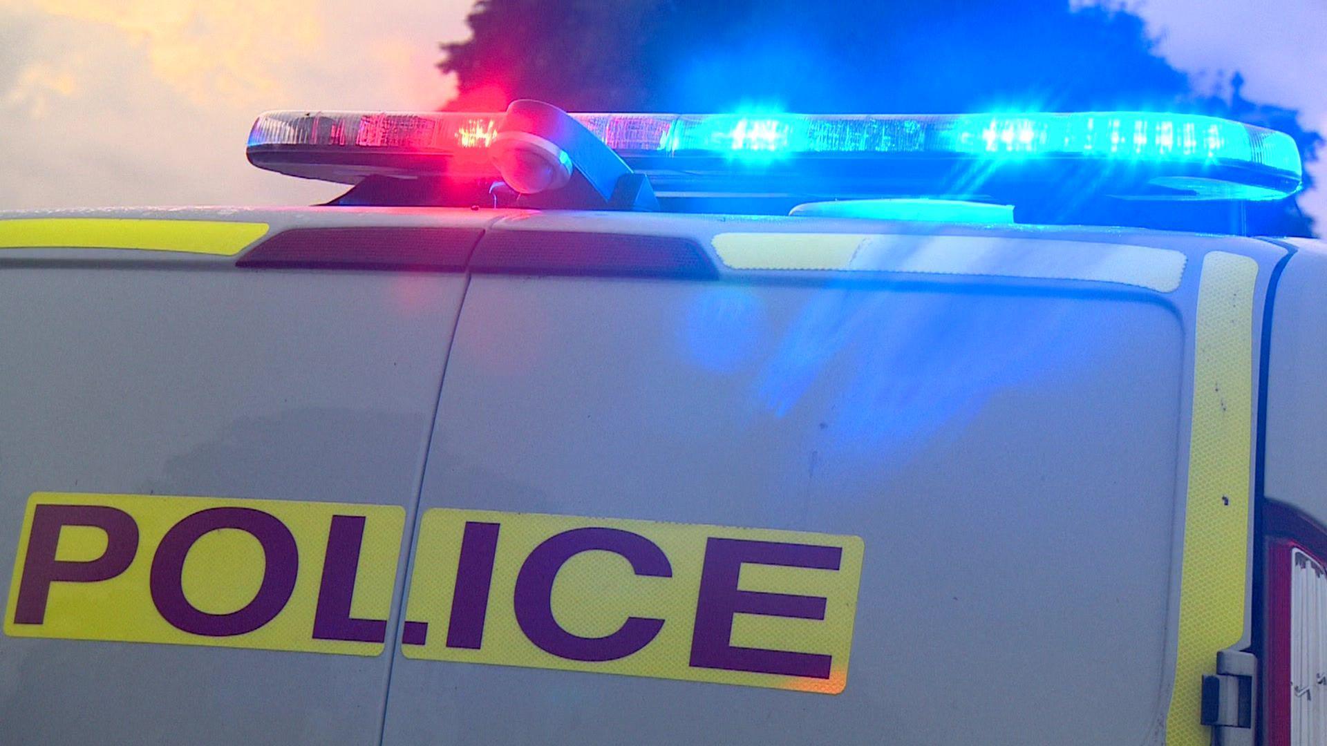 Part of the back of a police van with emergency lights on