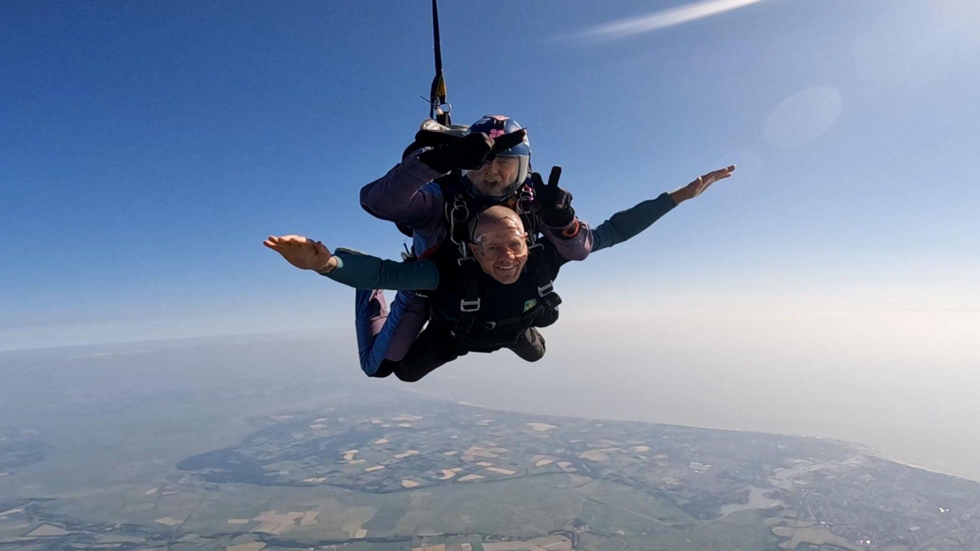 Phil Heckels (bottom) undertaking a skydive high in the sky with an instructor attached above him