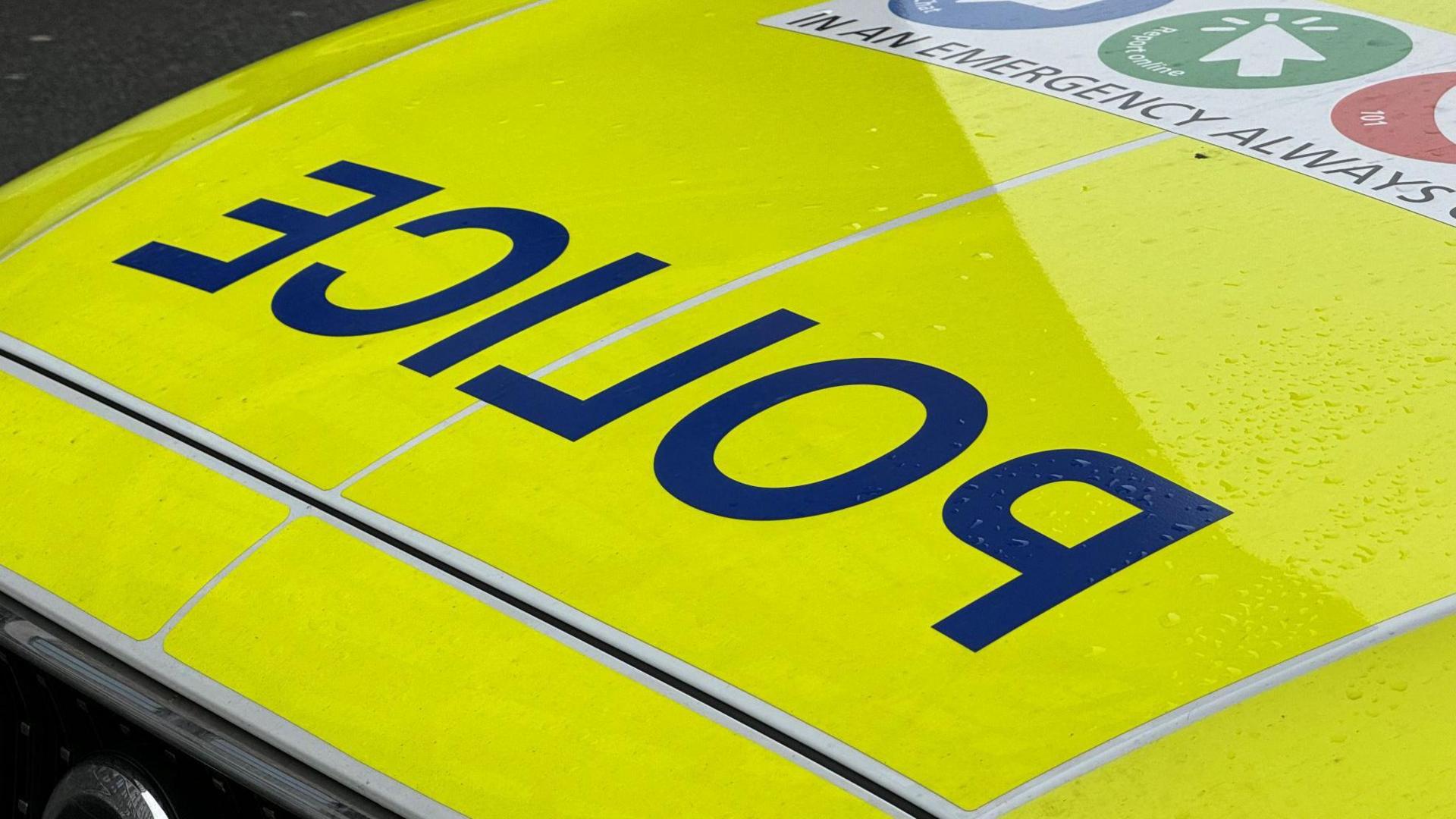 Police vehicle in Staffordshire. The car is yellow with a blue police sign and another sign which is partly visible and says "in an emergency" with pictures of who to contact. 