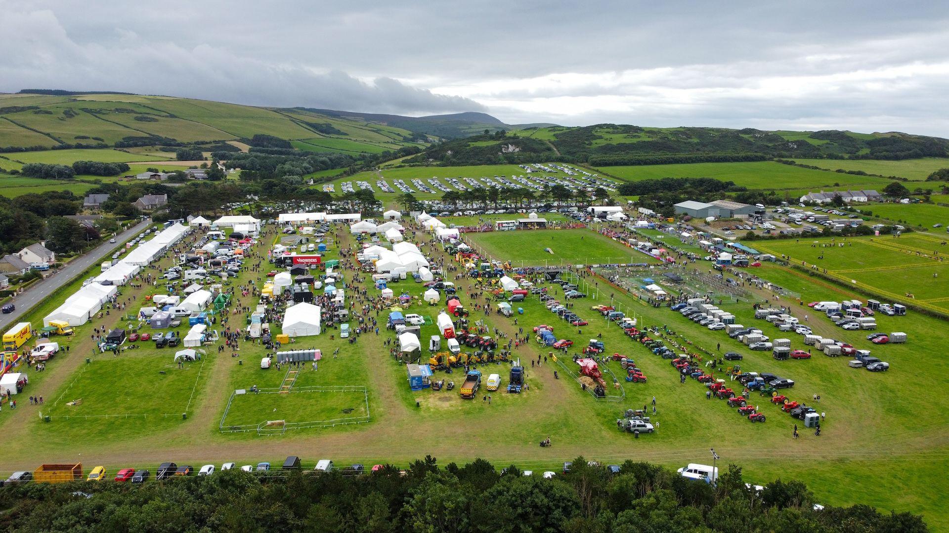 An arial shot of a large field with marquees and vehicles.