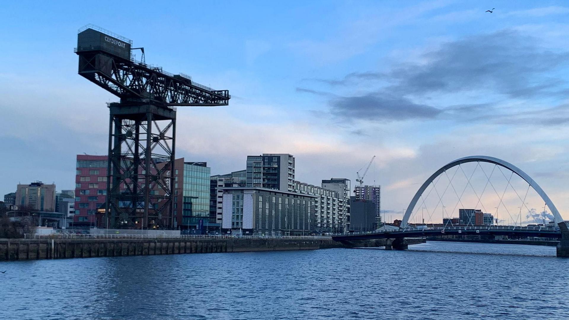 A giant crane in the left of picture stands next to the River Clyde and an arched bridge