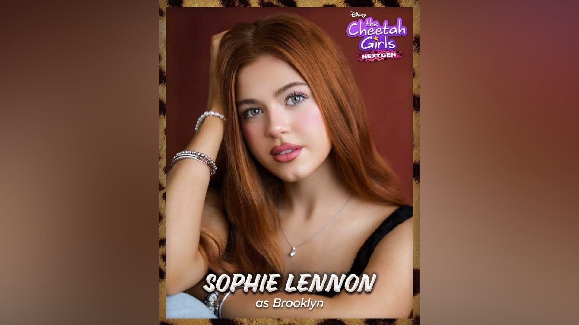 A teenage girl with long ginger hair. She is wearing pink lipstick and a black vest top. In the top right corner there is purple text that reads "The Cheetah Girls next gen".