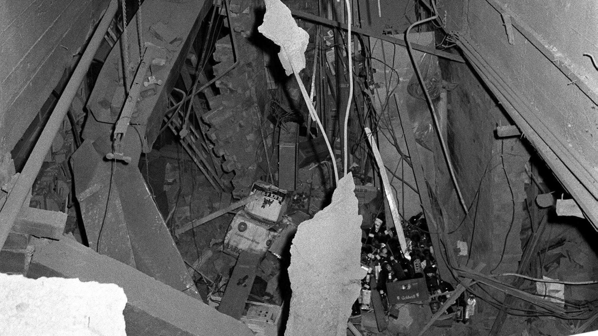 A black and white image taken from street level showing wreckage including exposed rafters, splintered wood and rubble