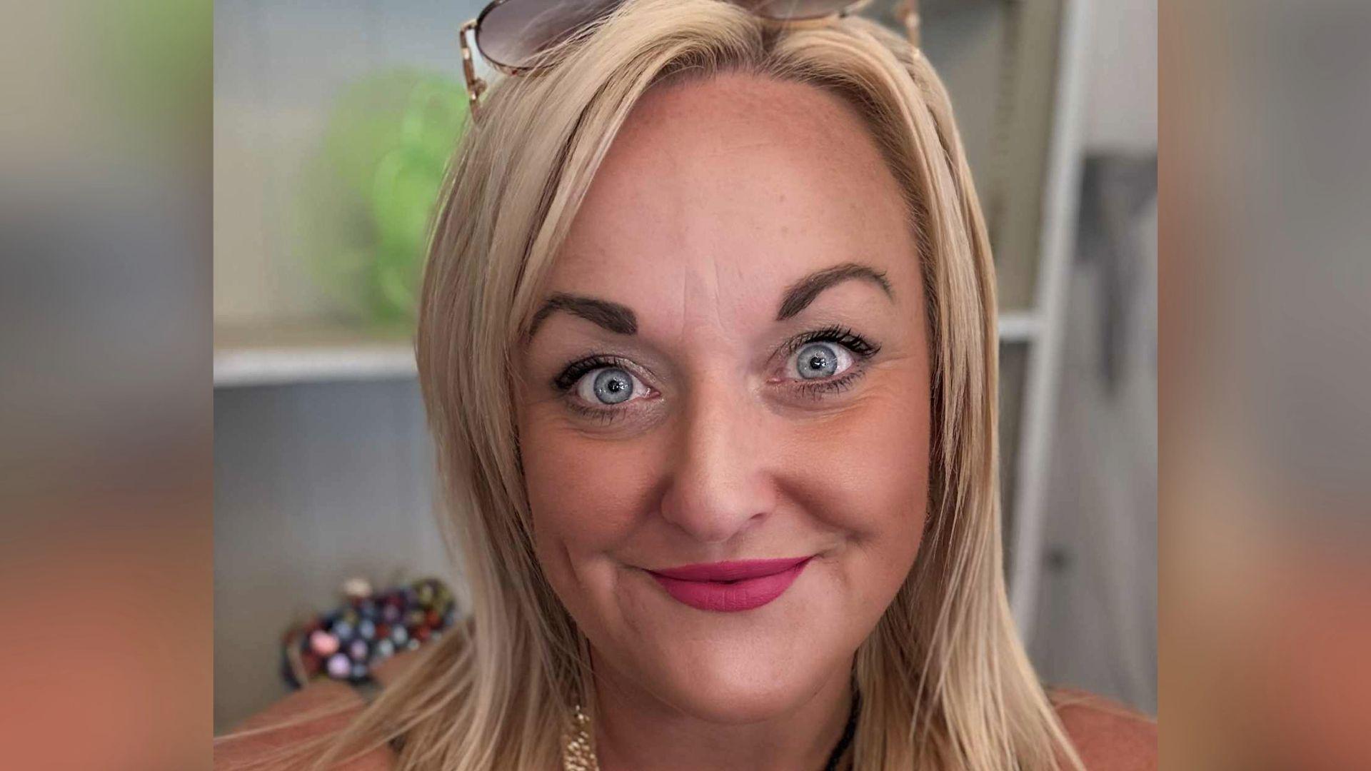Laura Mitchell, a woman with blonder hair, with a pair of sunglasses on top of her head is looking directly at the camera.